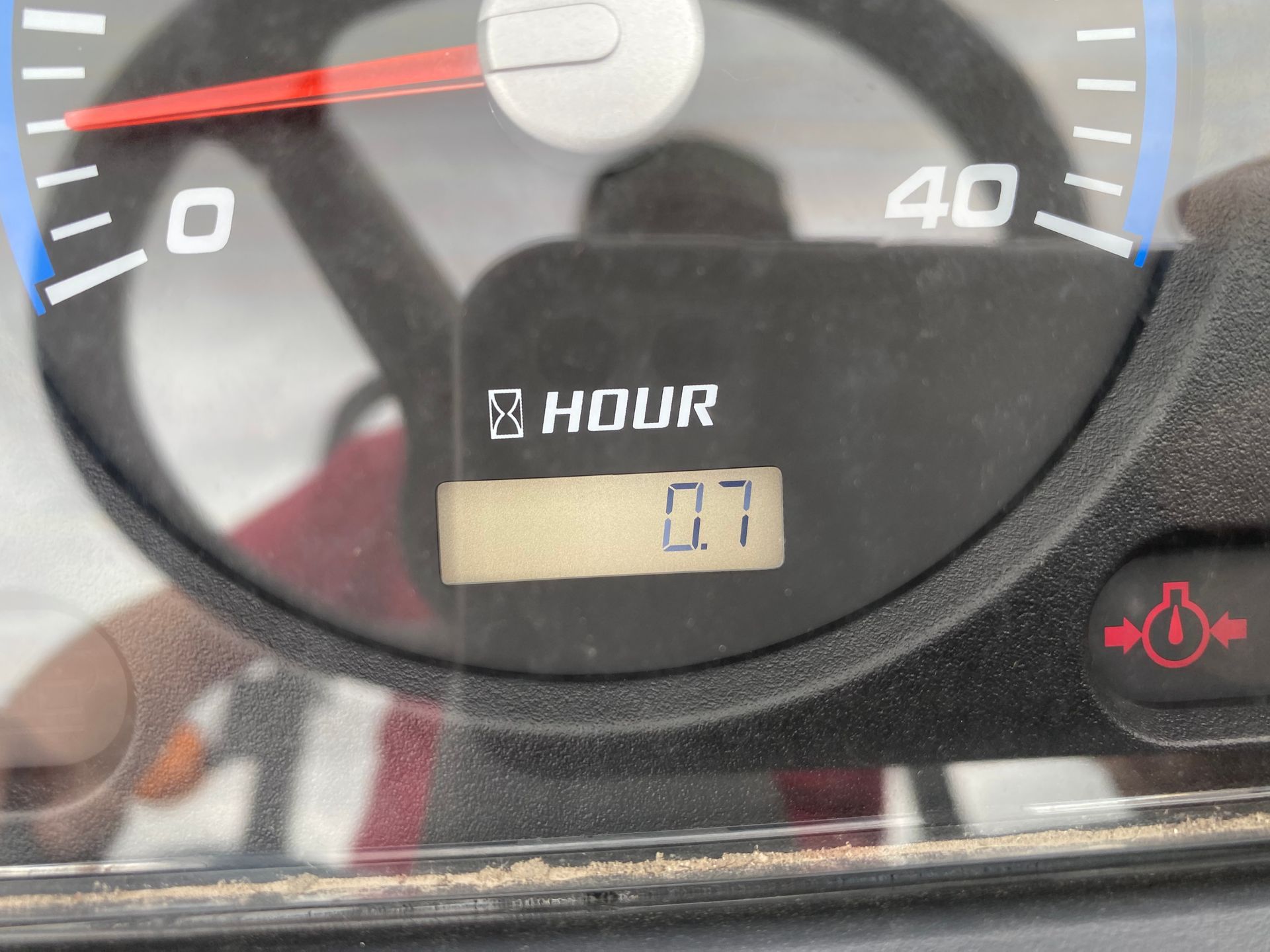 Close-up of a tractor dashboard displaying 0.7 hours of use. Gauges and a steering wheel are visible.
