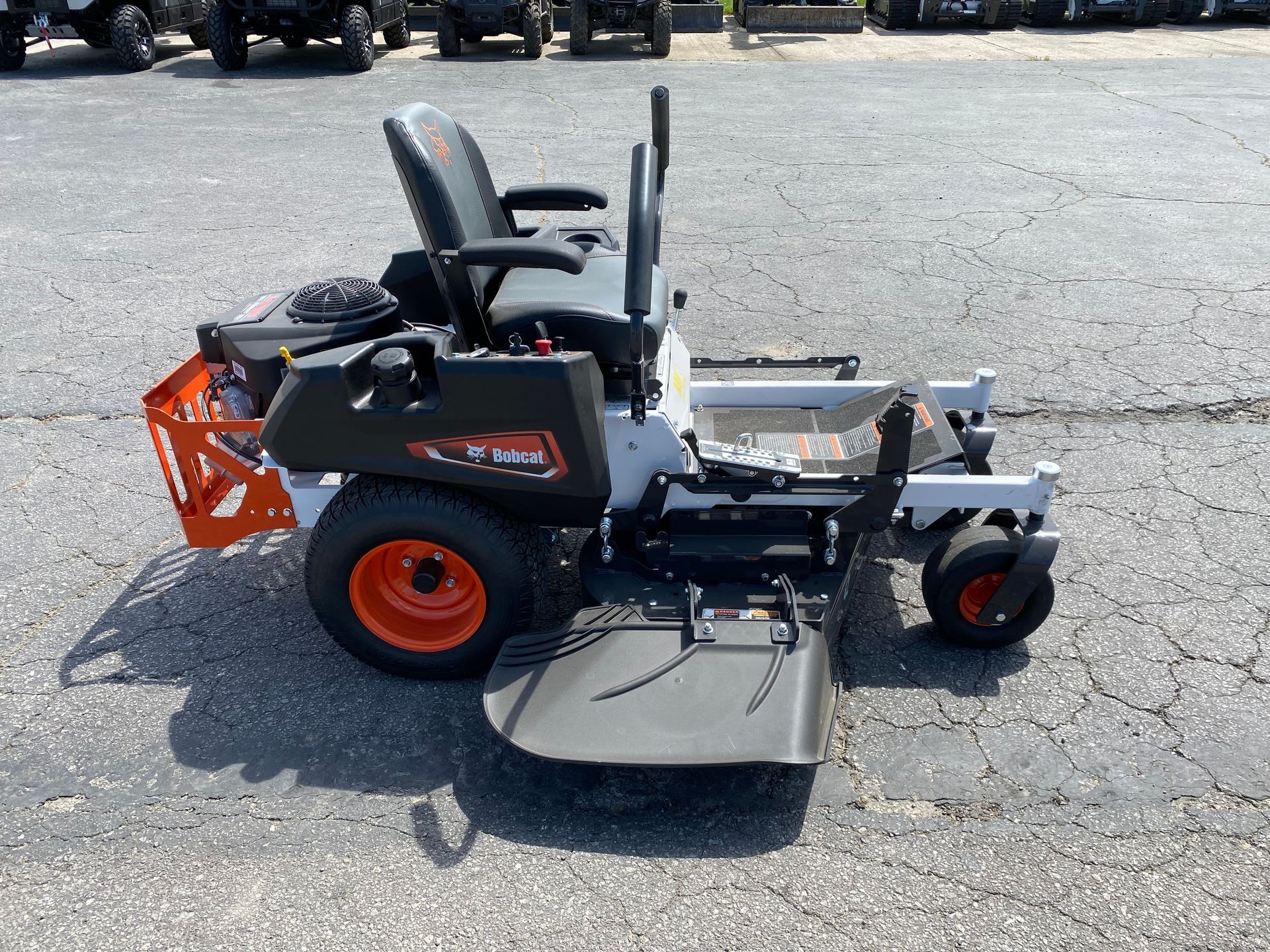 Bobcat zero-turn mower on a paved surface. Features orange wheels and a black seat and frame.