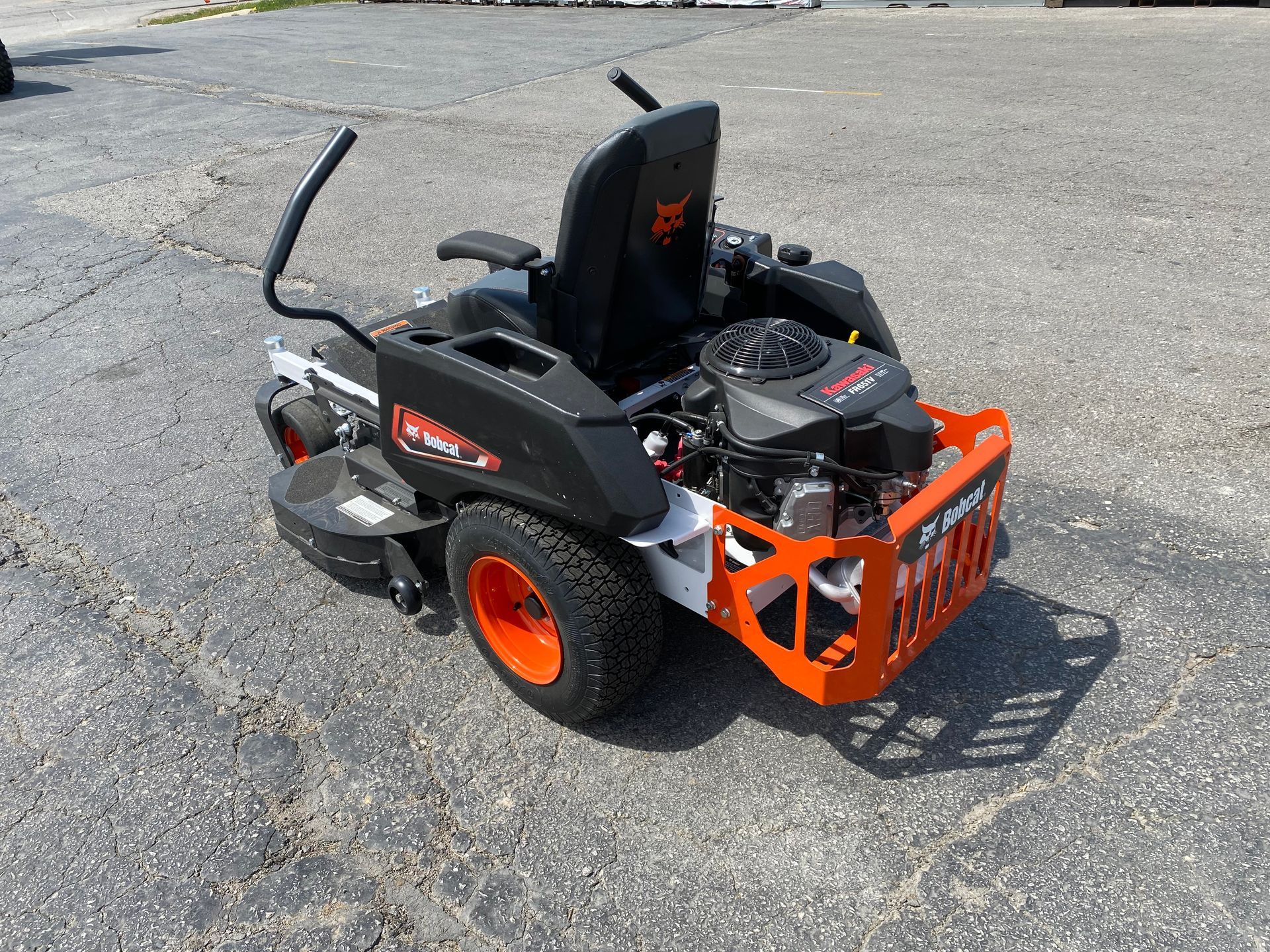 Black and orange Bobcat zero-turn mower on asphalt, angled shot.