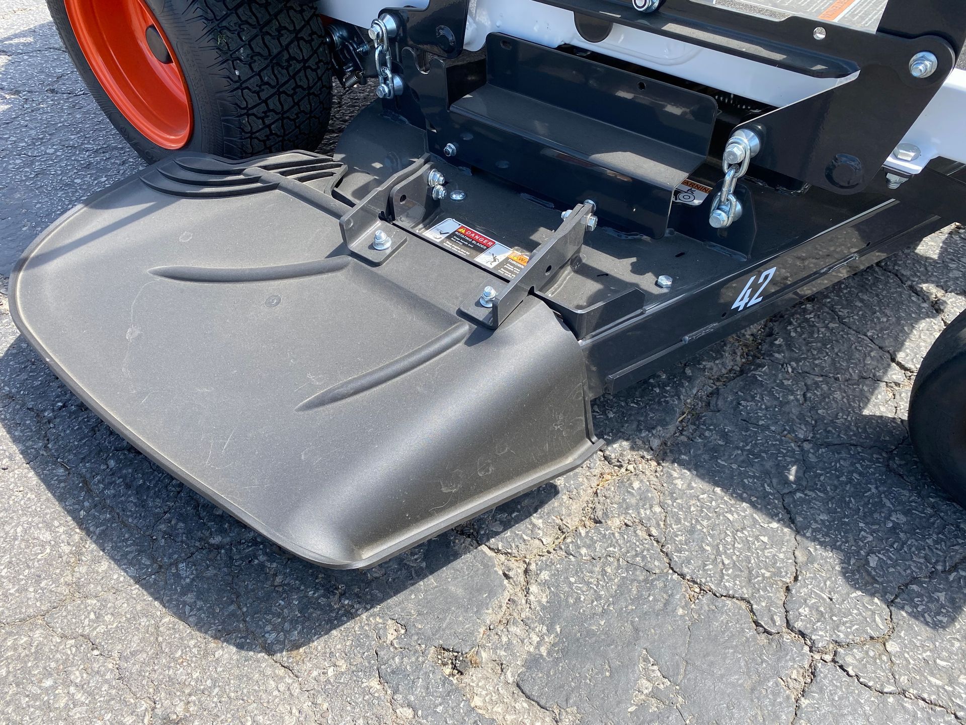 Close-up of a black mower deck on a Bobcat mower, with a tire in the background.