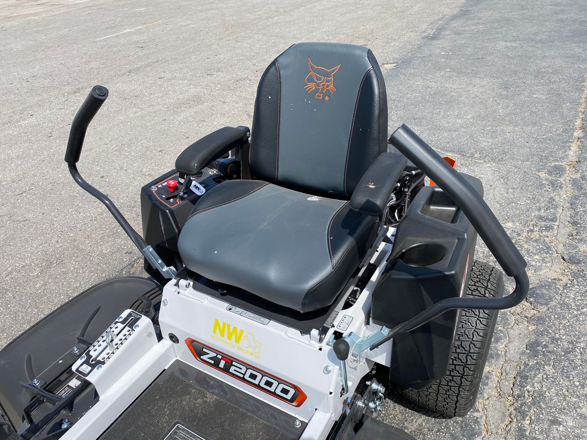 Zero-turn lawnmower, white and black, with a seat, control arms, and a cup holder.