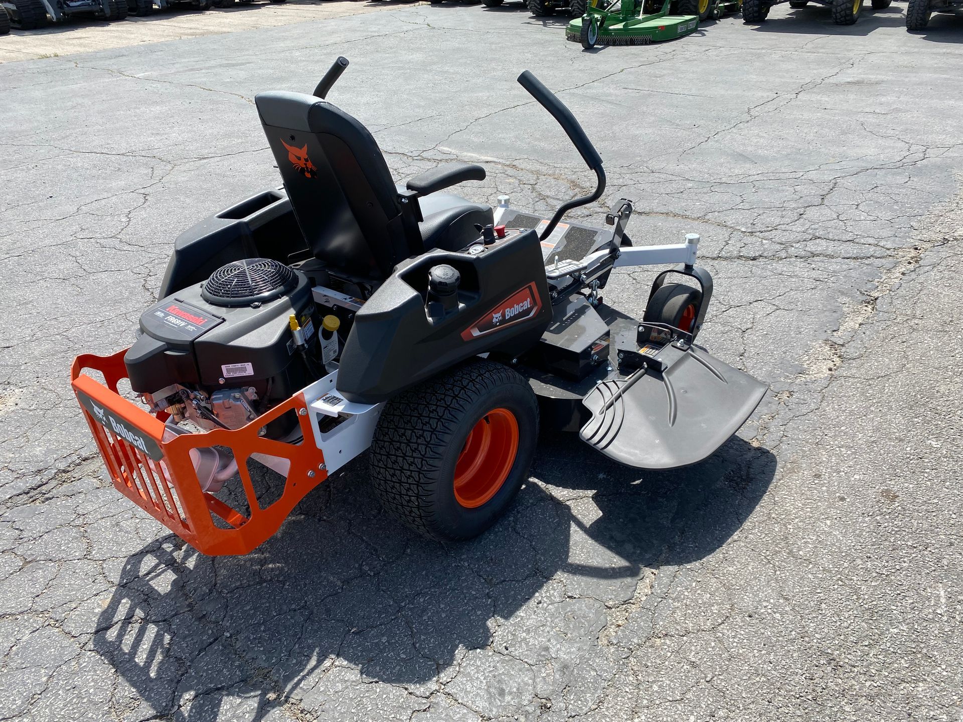 Orange and black zero-turn lawnmower on pavement.