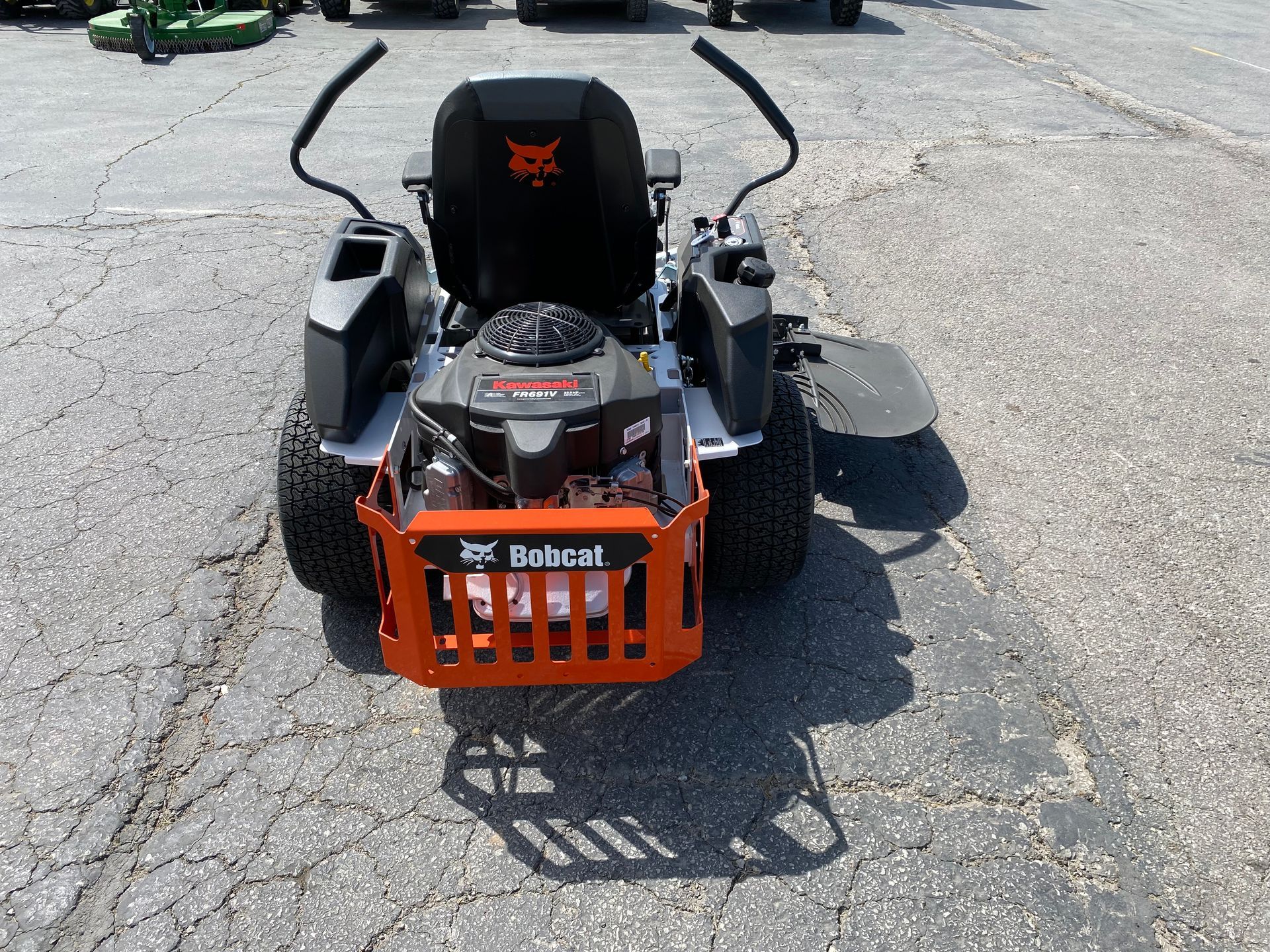 Bobcat zero-turn mower, orange and black, parked on asphalt.