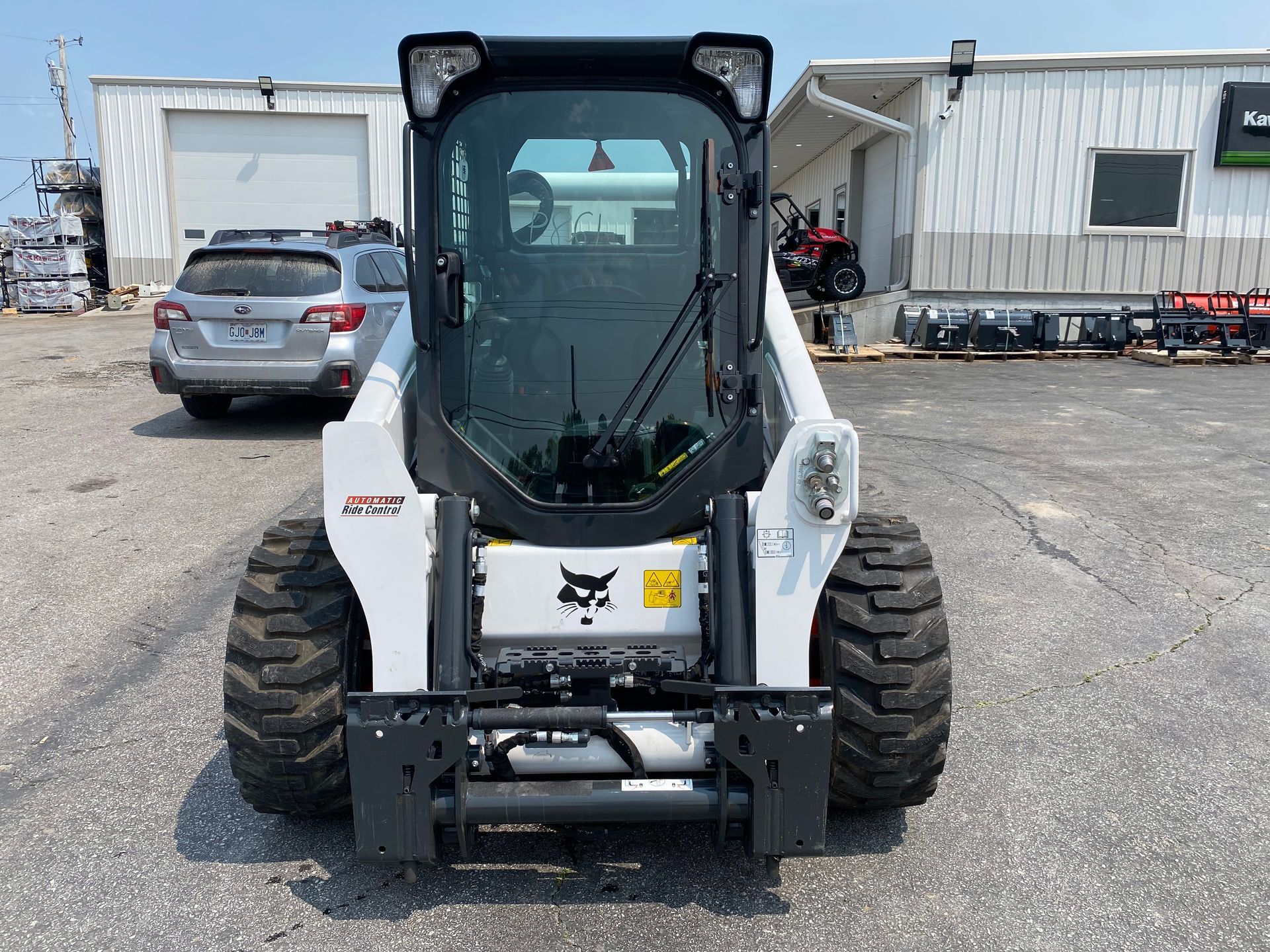 White Bobcat skid-steer loader parked outdoors, viewed from the rear, with dark tires and a cab.