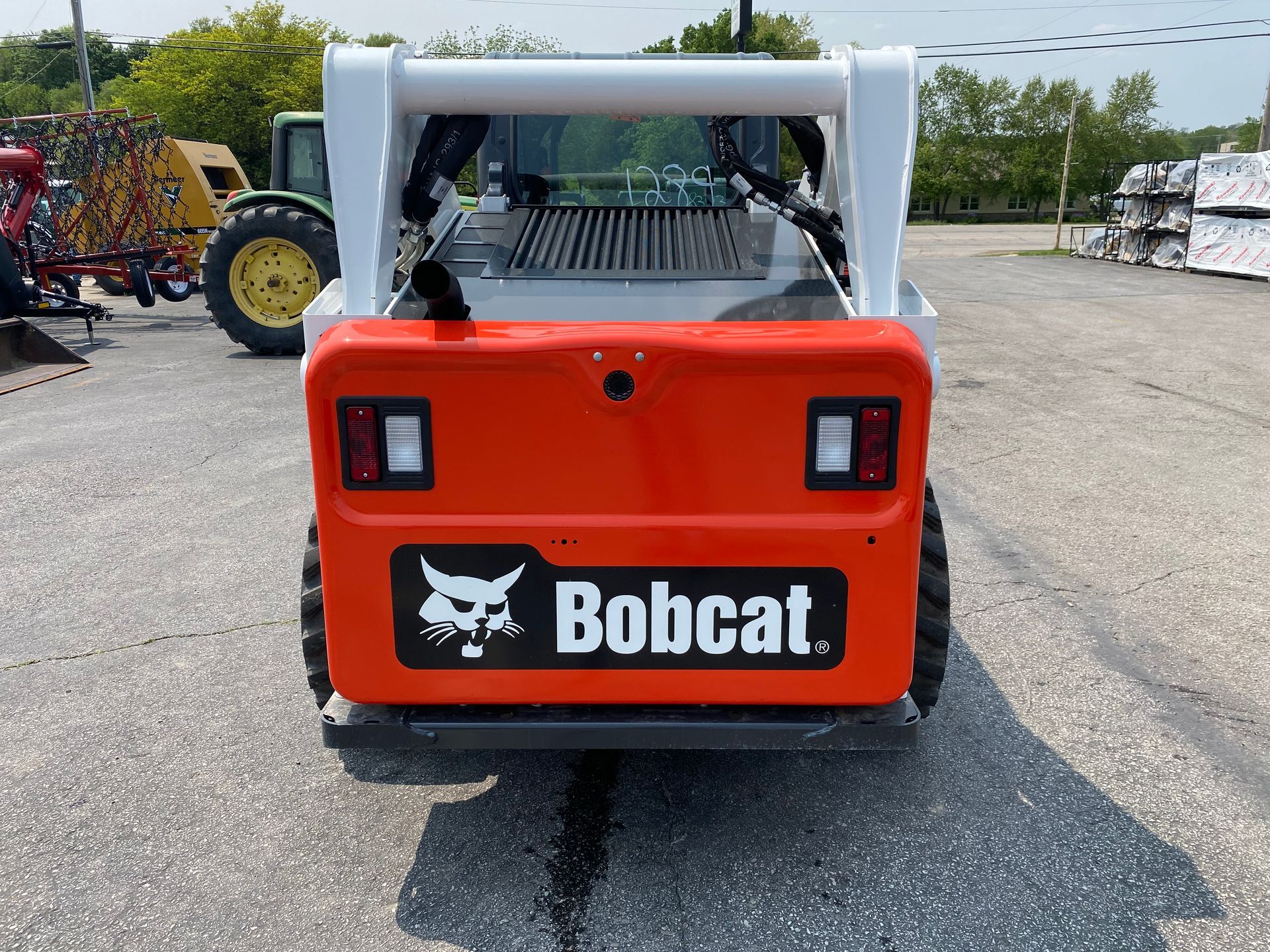 Rear view of an orange and white Bobcat skid-steer loader with black tires, logo, and lights.