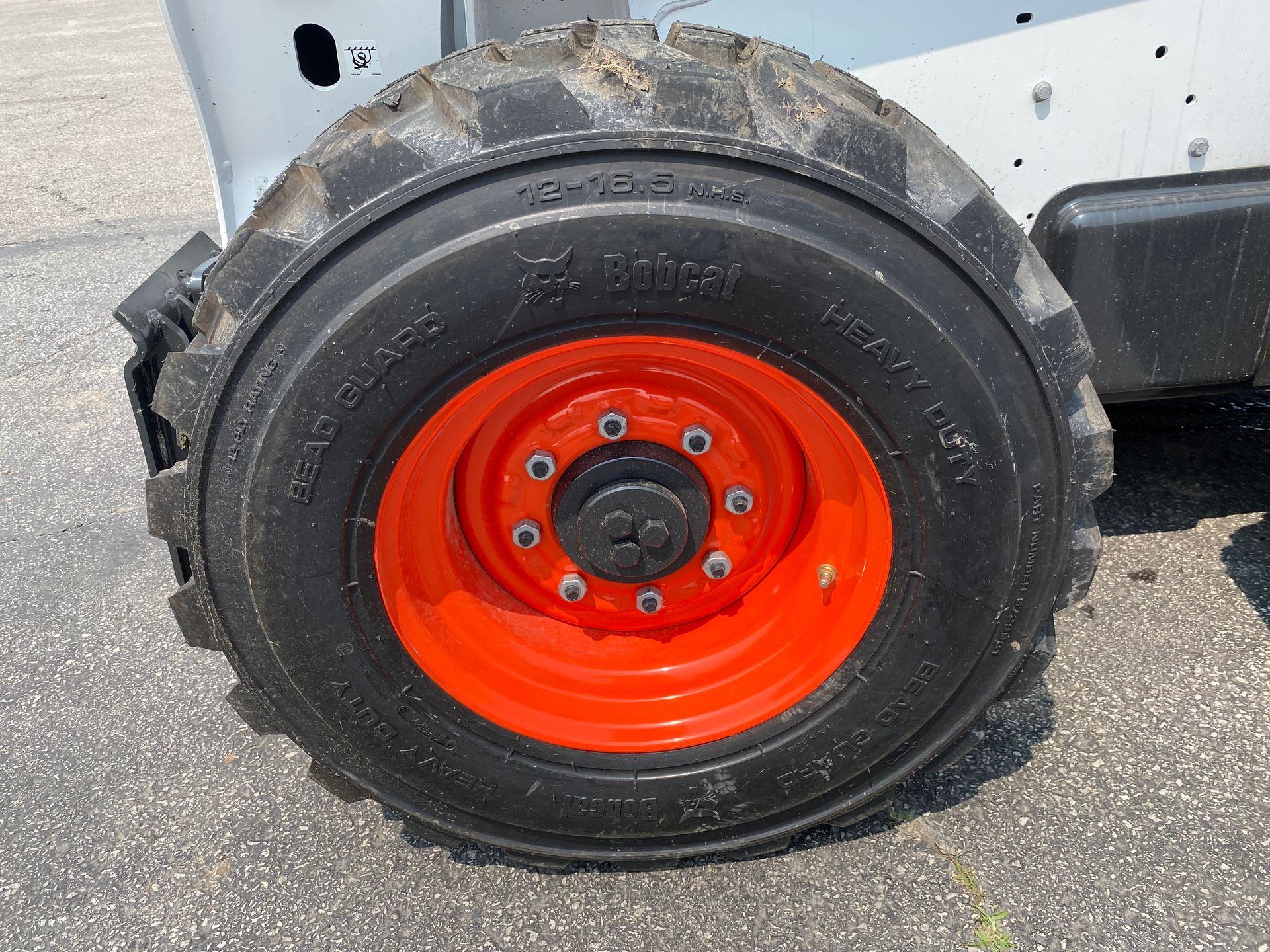 Black tire on an orange wheel; part of a Bobcat heavy machine.