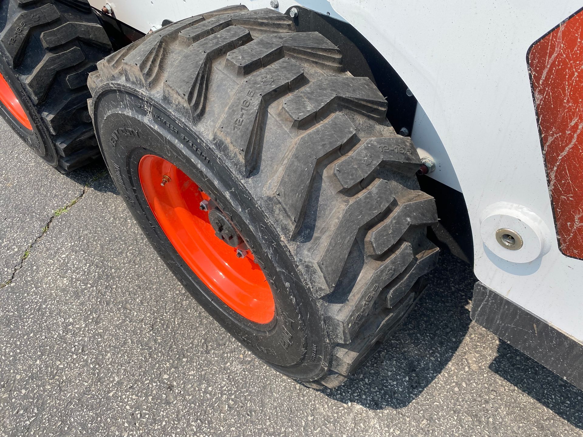 Close-up of a Bobcat skid-steer loader wheel with black treads and an orange rim.