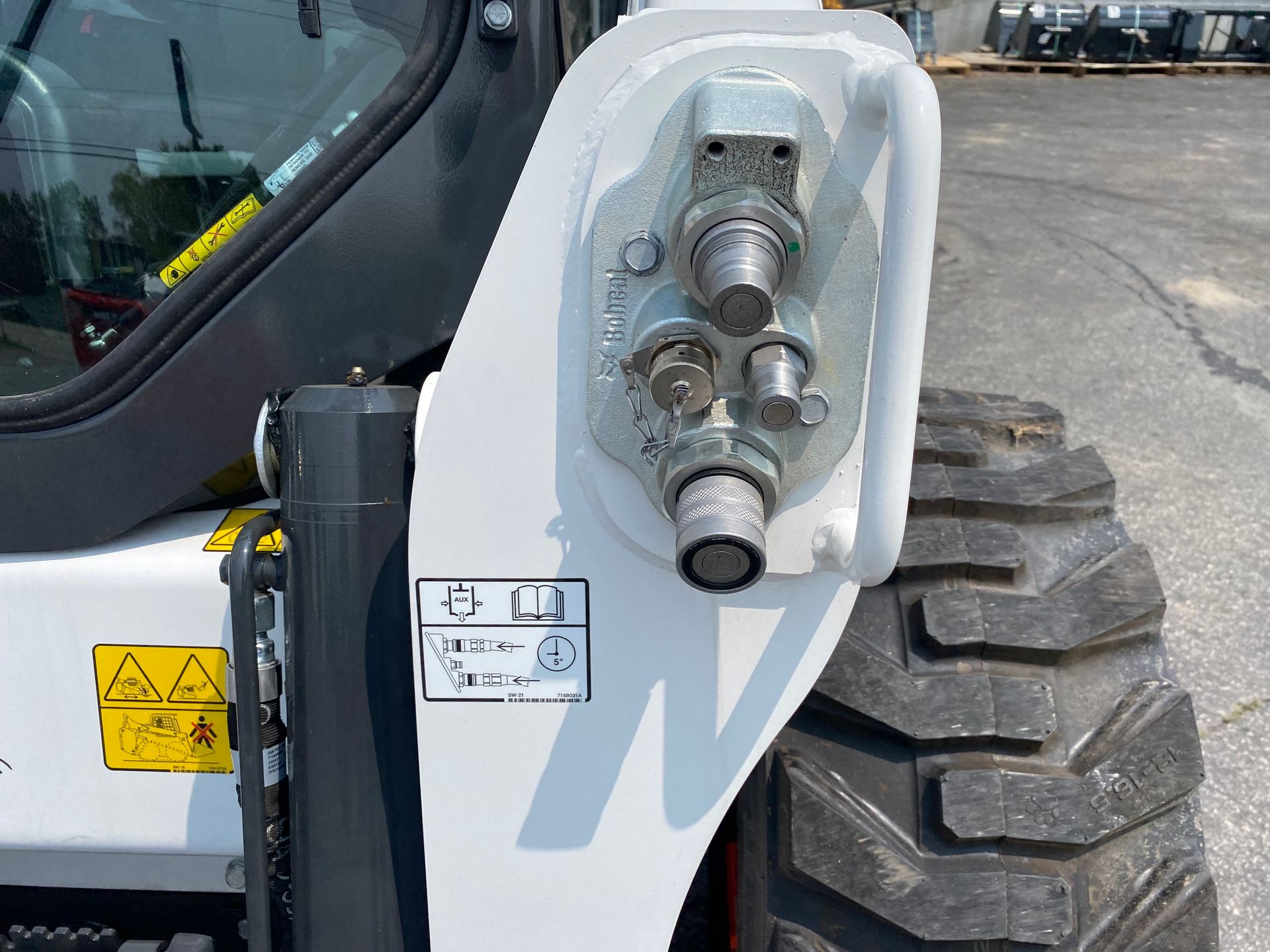 Hydraulic coupler and tire on a white Bobcat skid steer loader.