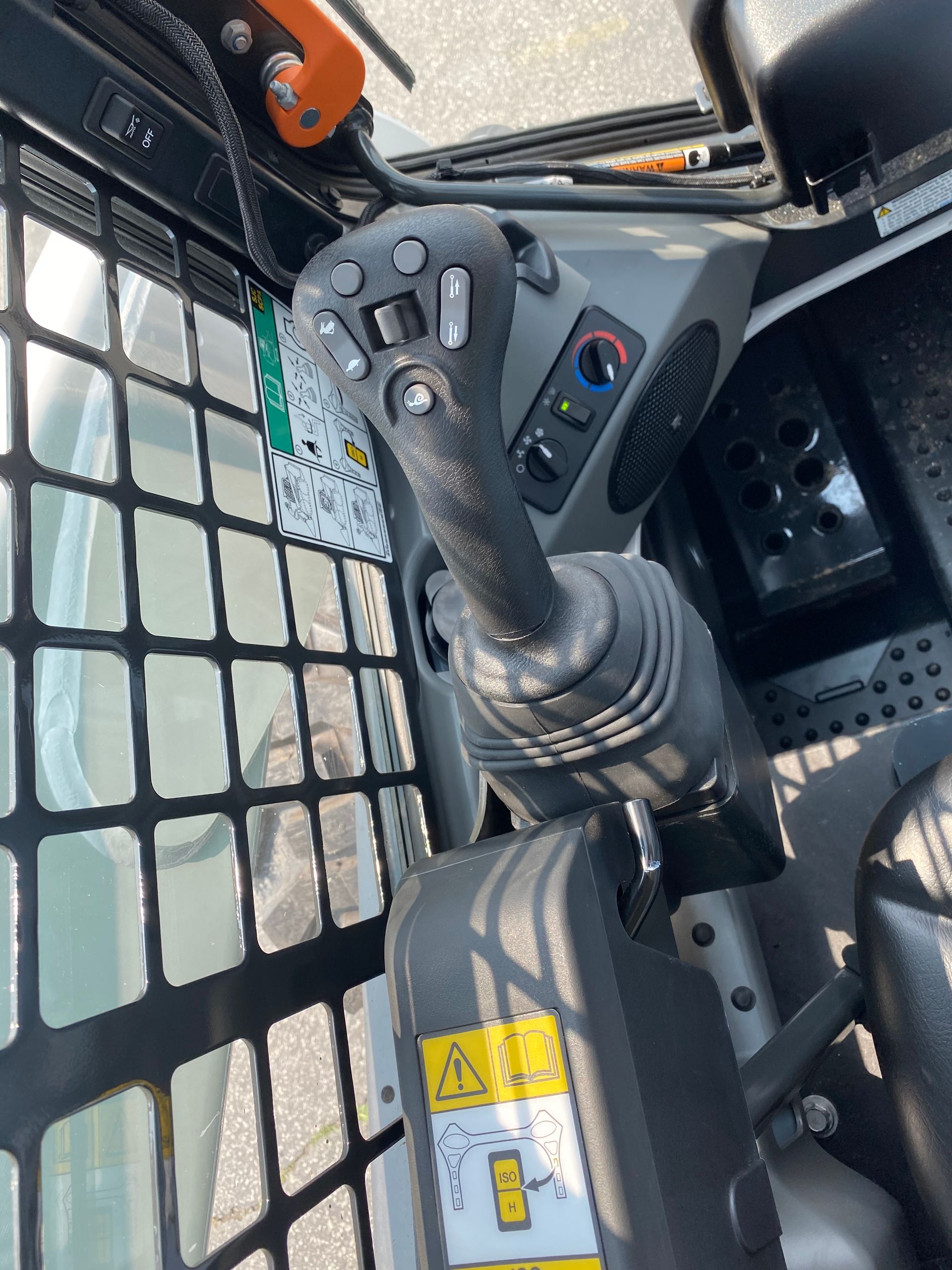 Interior view of a skid steer loader control panel, showing joystick and cabin controls.