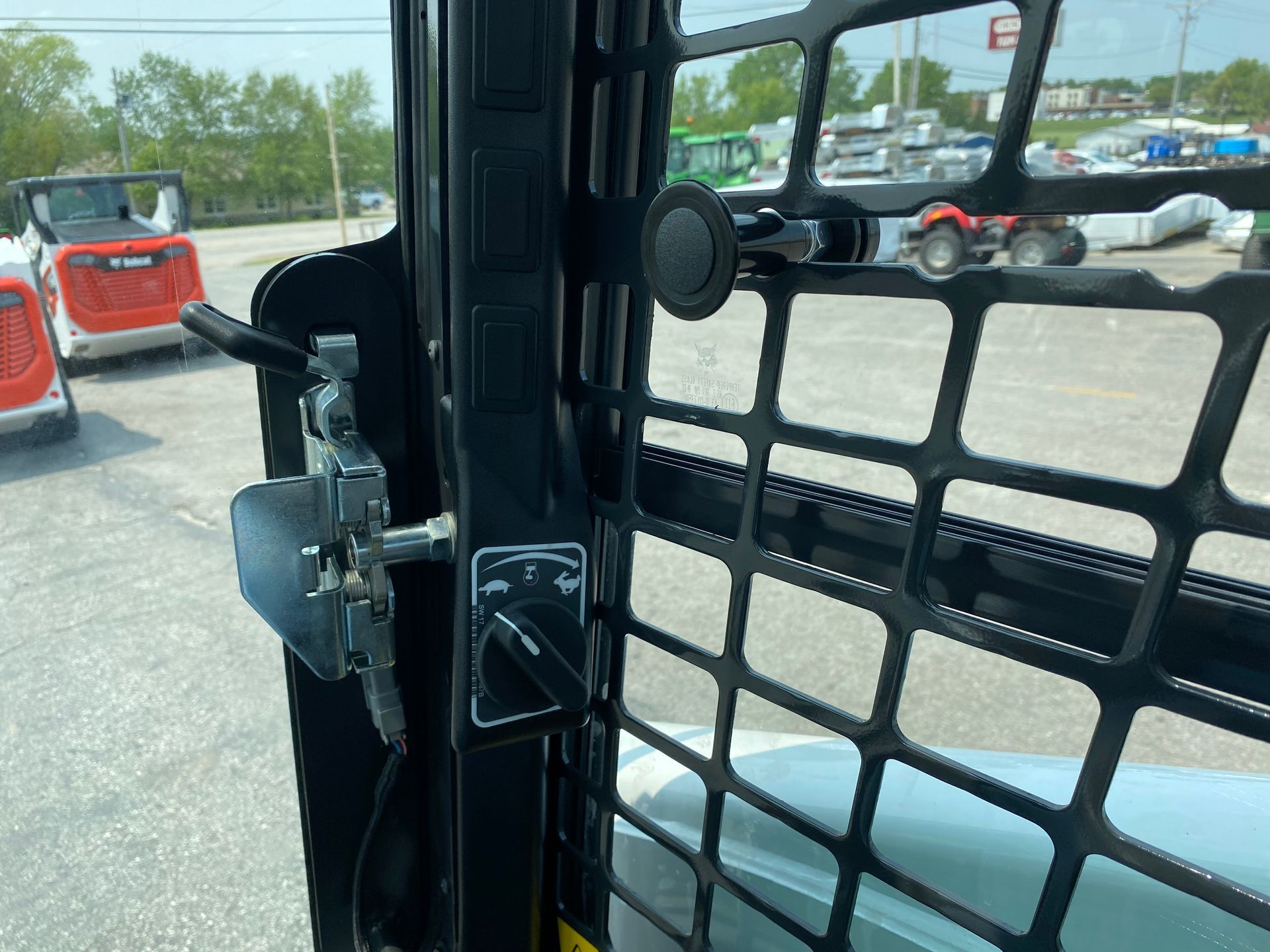 Interior of a Bobcat skid-steer cab with a black safety cage, handle, and switches.