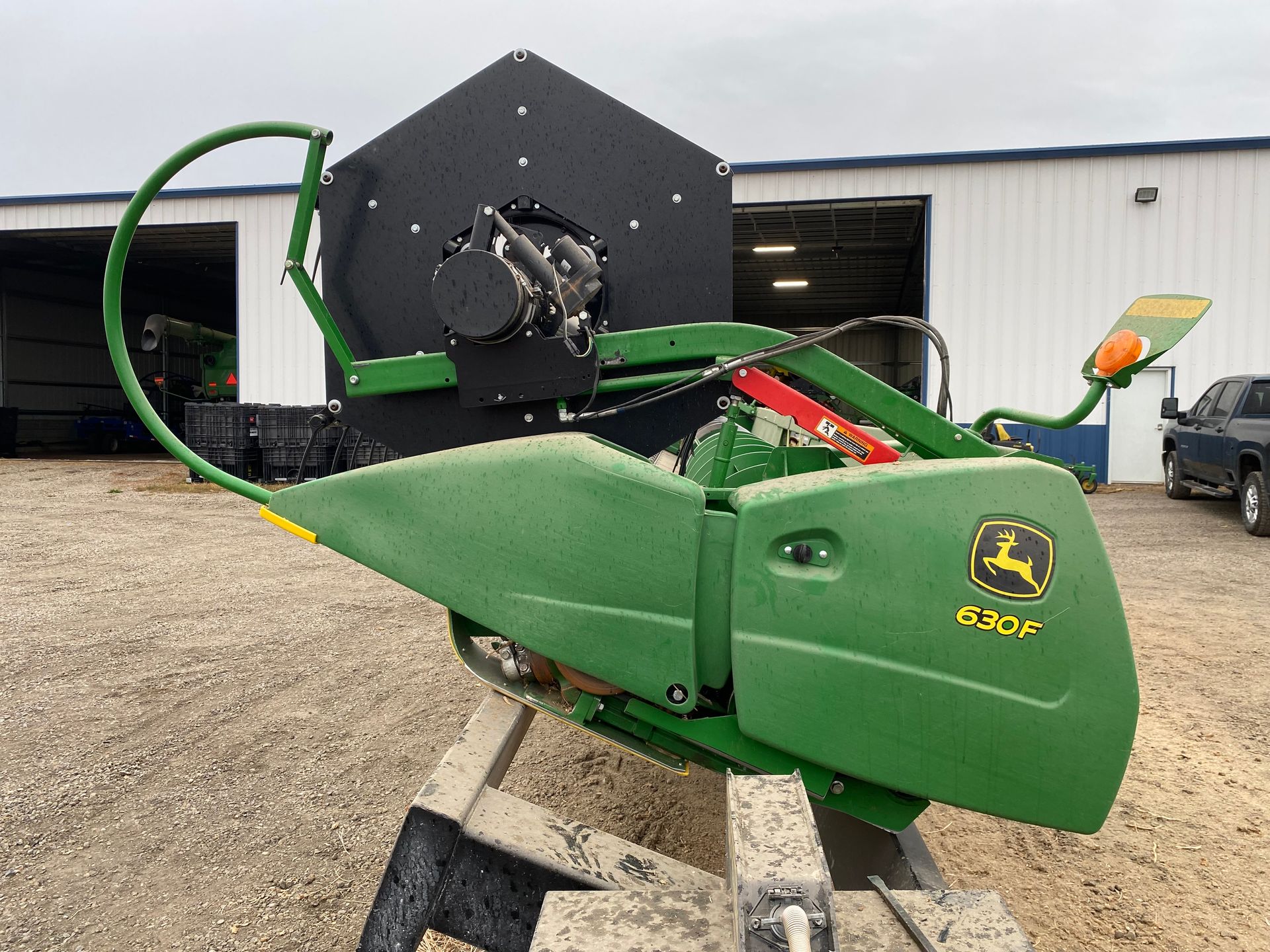 John Deere 620F corn head, green and black, on a stand outdoors.
