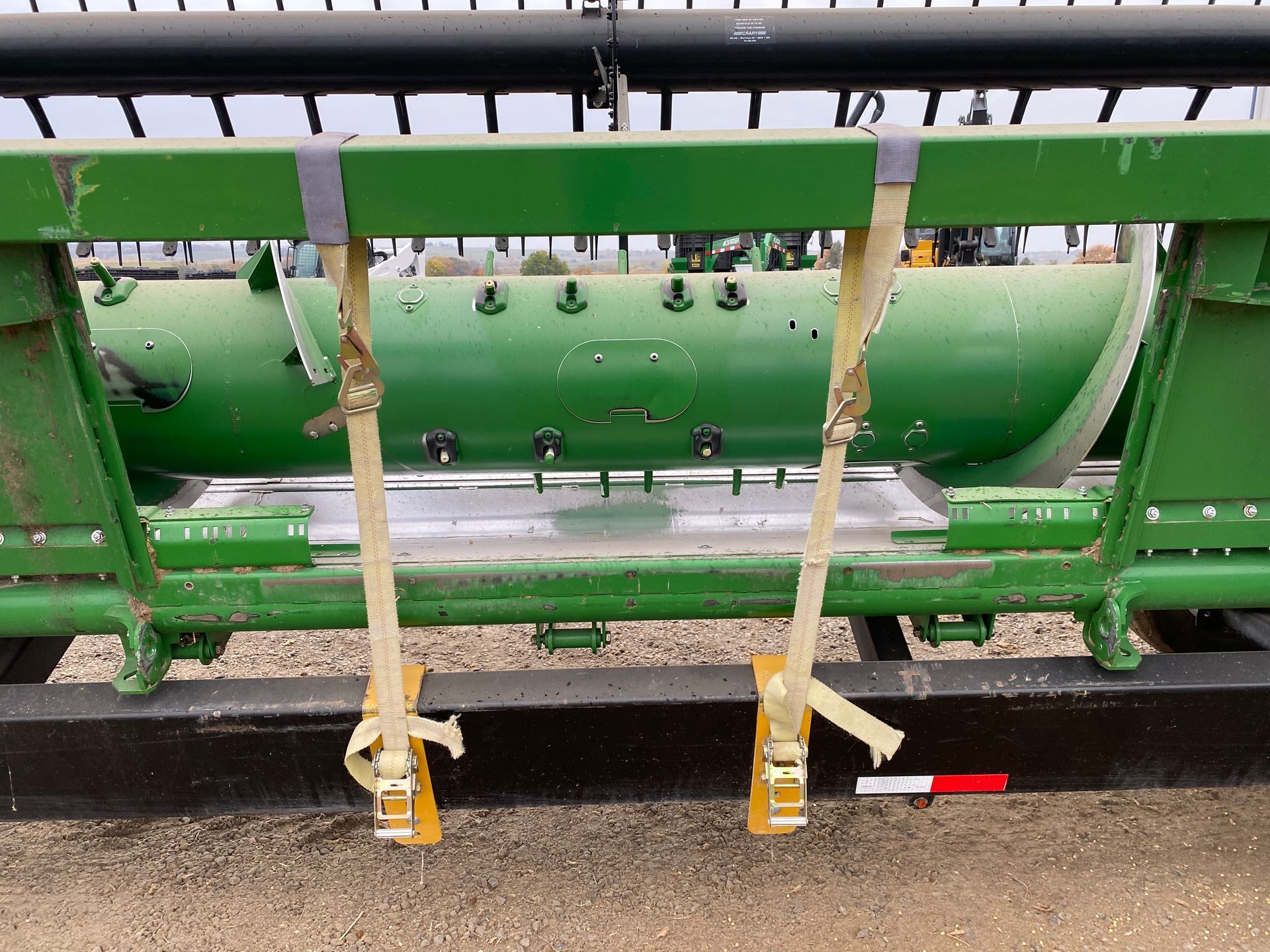 Green combine header secured with yellow straps.