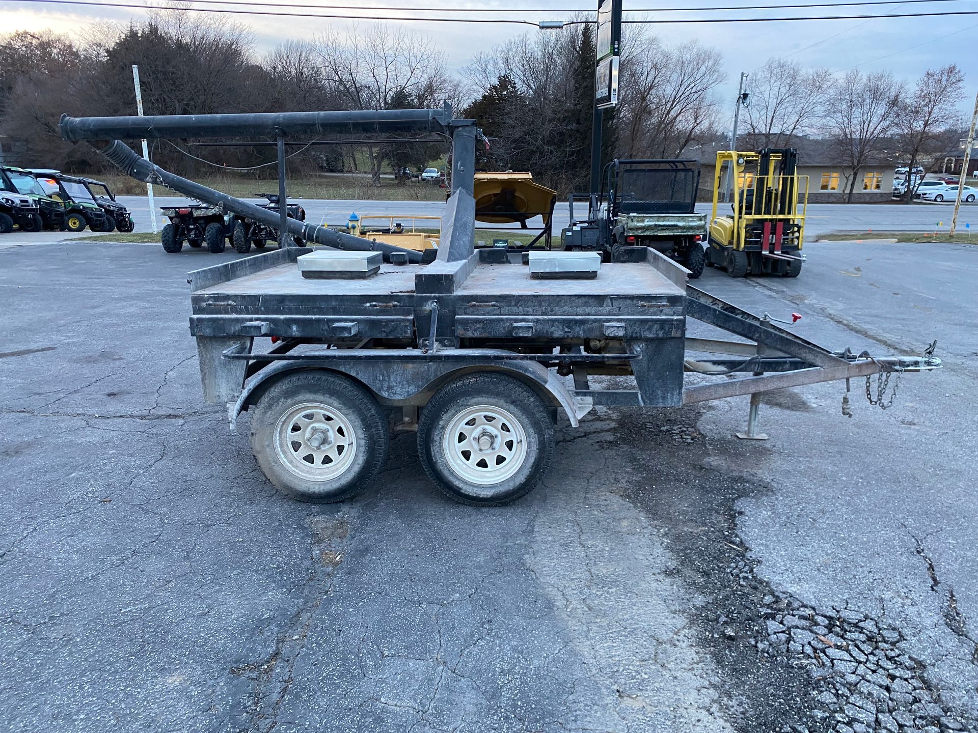 Black utility trailer with two wheels, parked on asphalt.