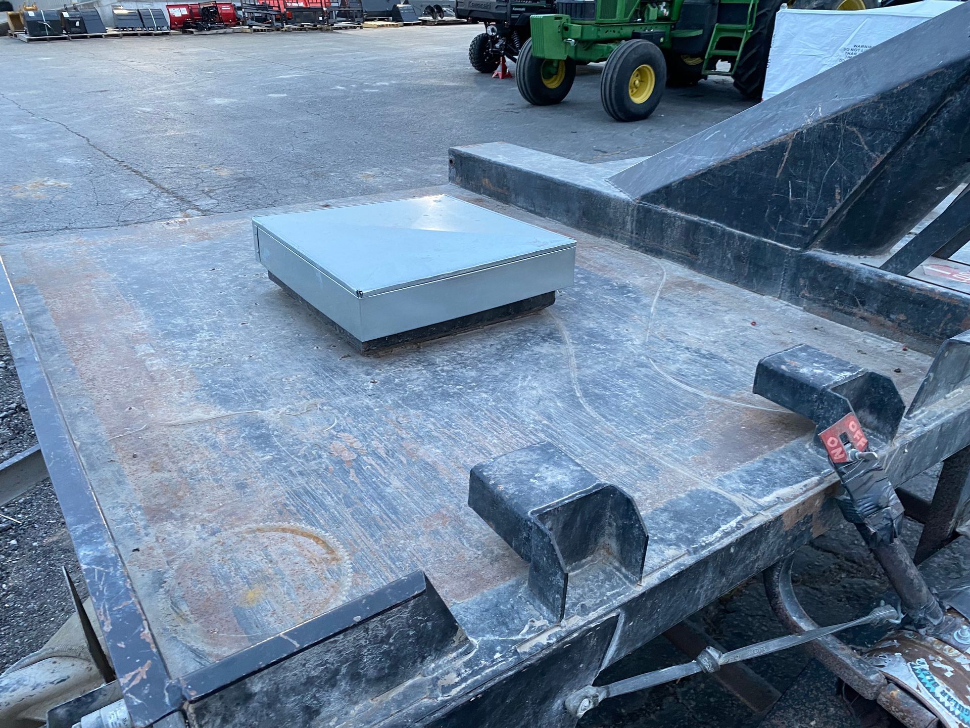 Metal machinery platform with a gray box on top. In an outdoor setting.