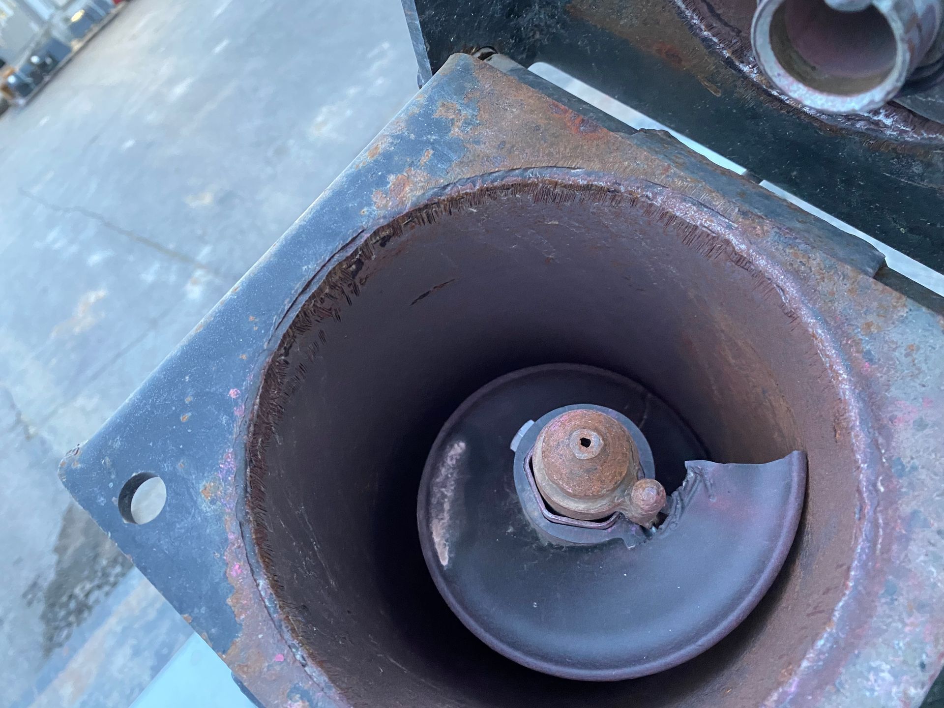 Rusty metal cylinder with broken spiral disc inside.