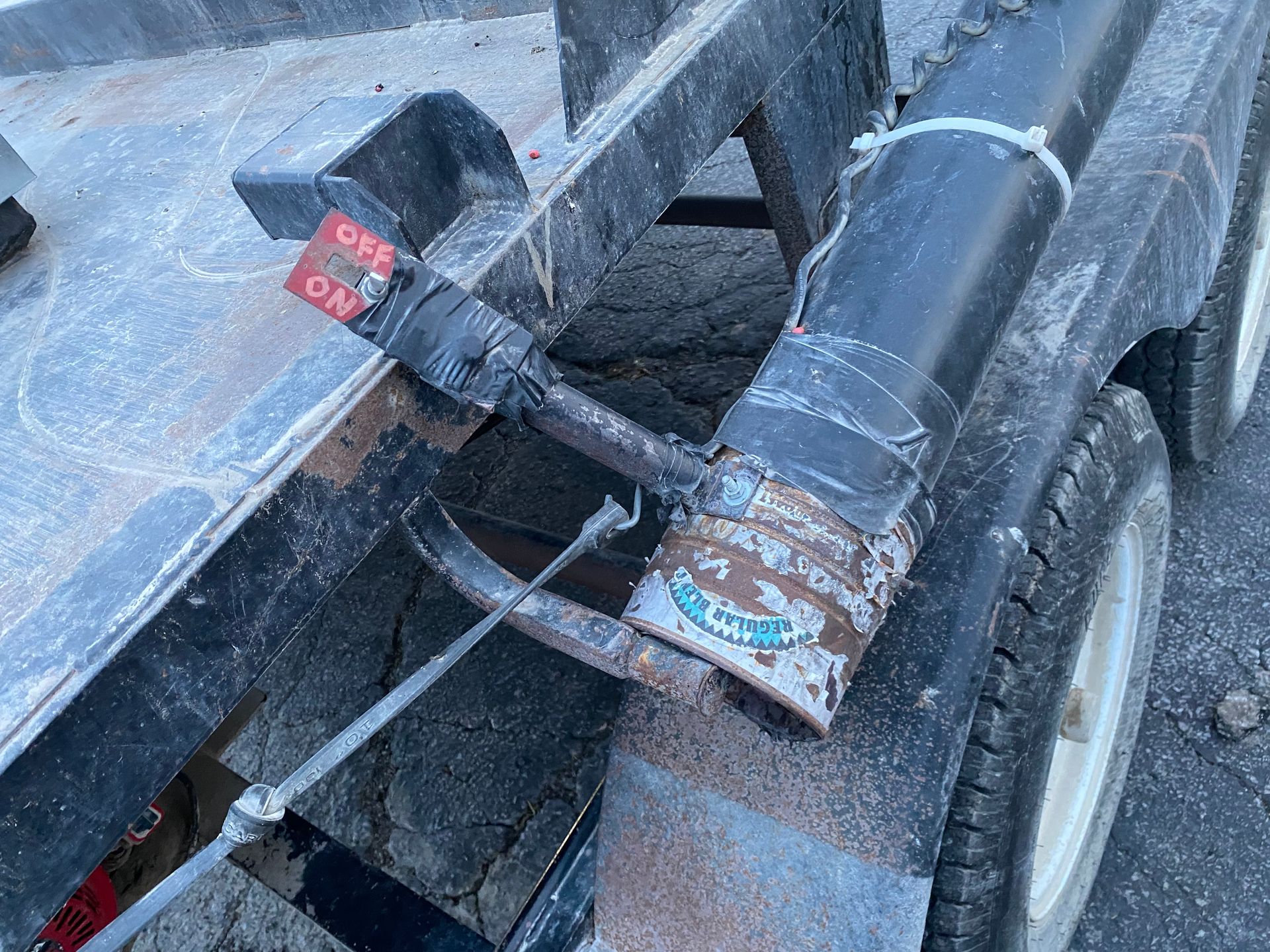 Black equipment mounted on a trailer; includes a lever labeled 