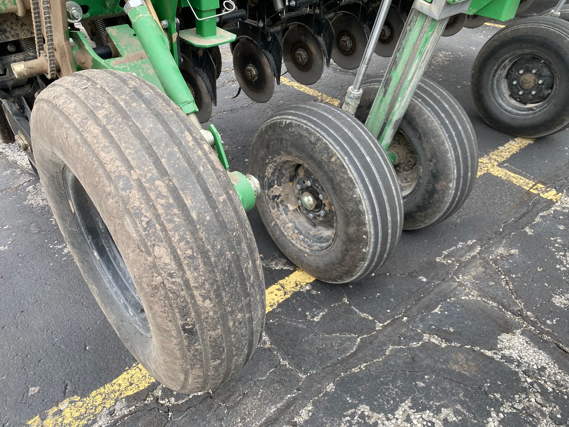 Close-up of agricultural machinery tires, outdoors on asphalt, showing dirt and wear.