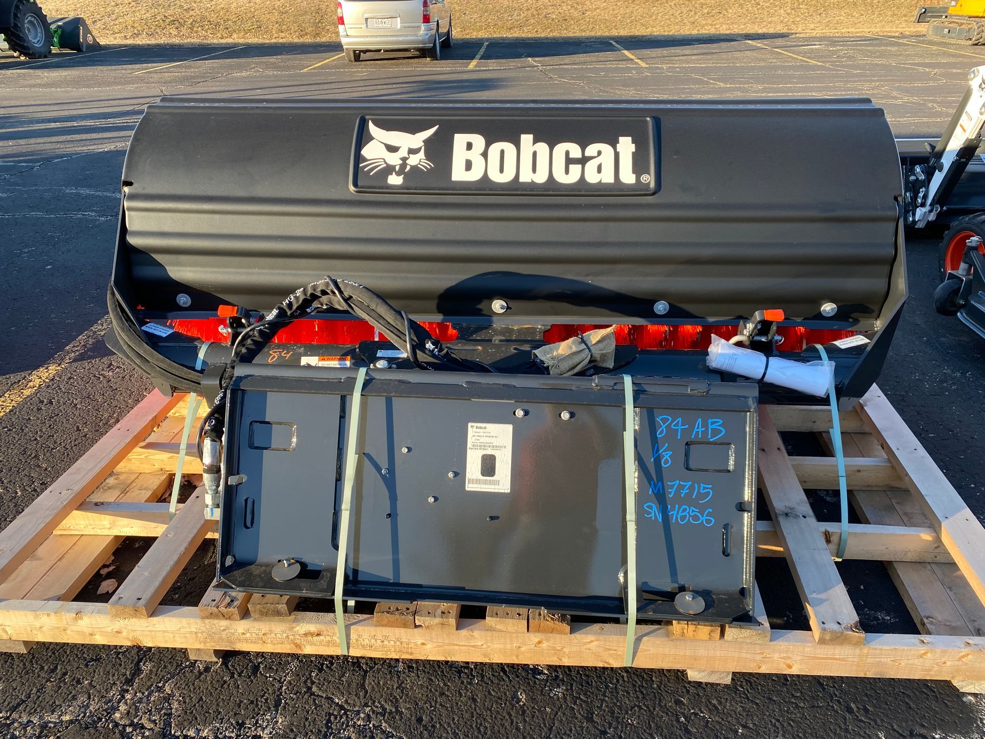 Bobcat snow blade attachment on a wooden pallet. Black and red.