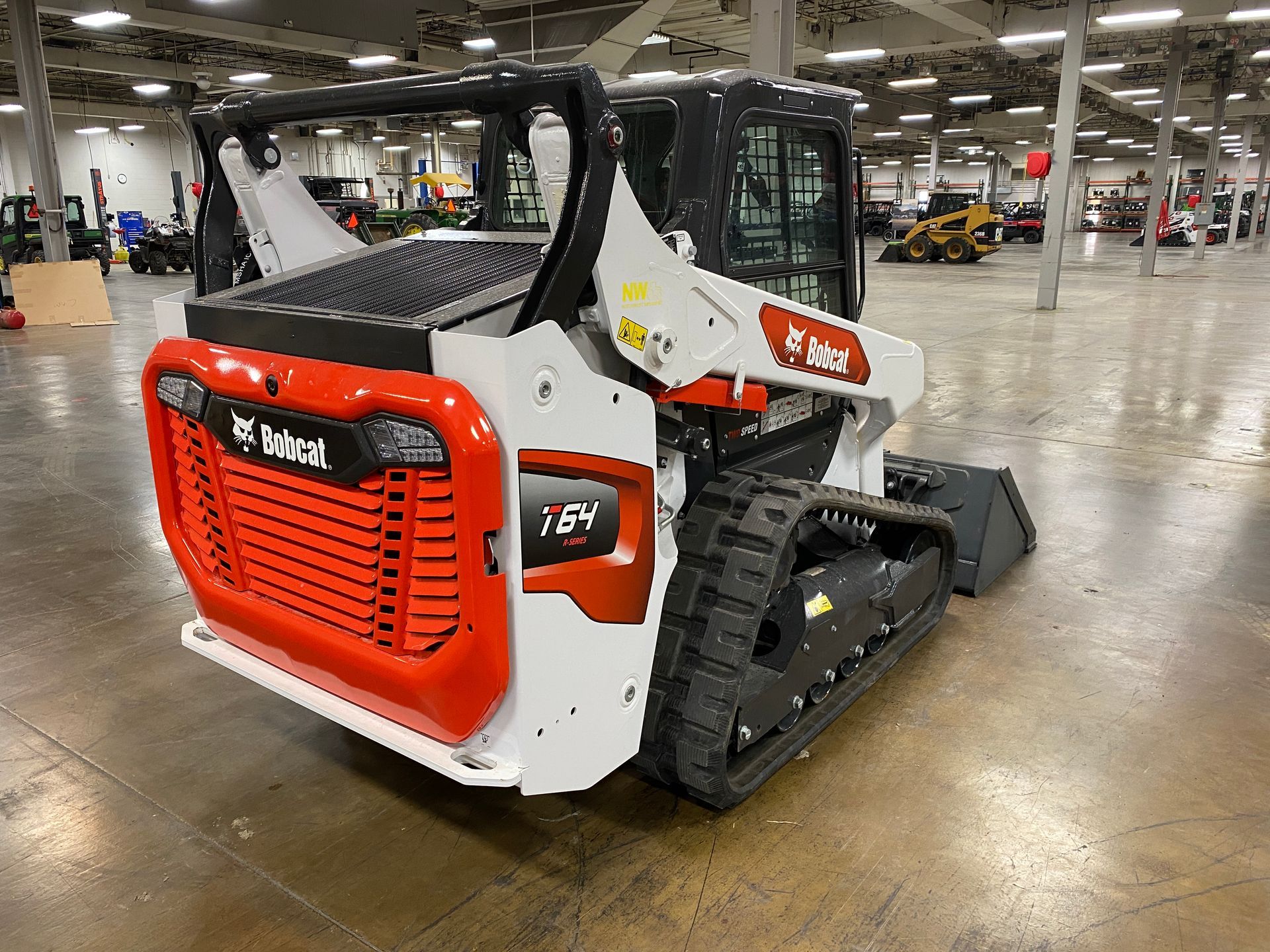 Bobcat T64 compact track loader, white and orange, indoors.