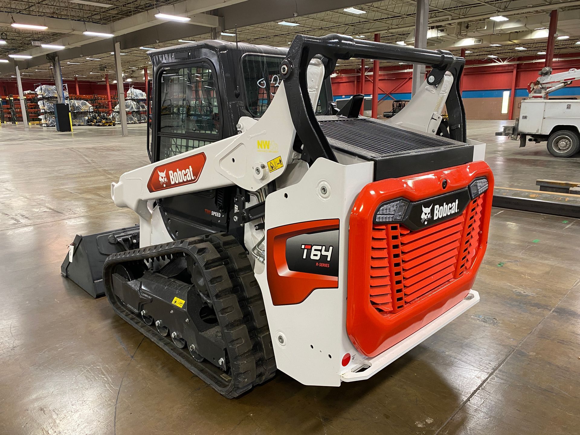 Bobcat T64 compact track loader, white and orange, indoors.