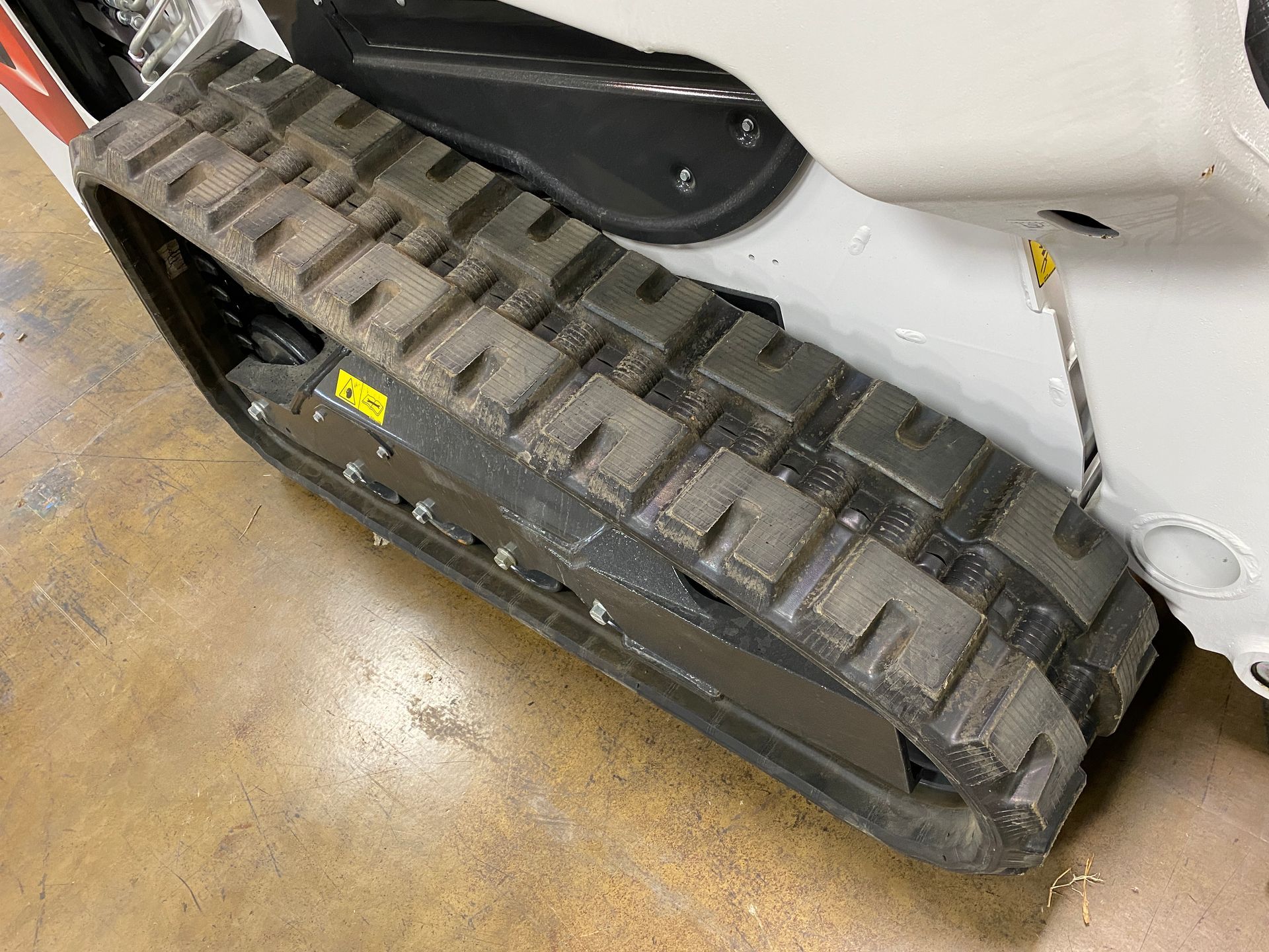 Close-up of a tread on a white and black construction vehicle. The tread is dark gray and shows wear.