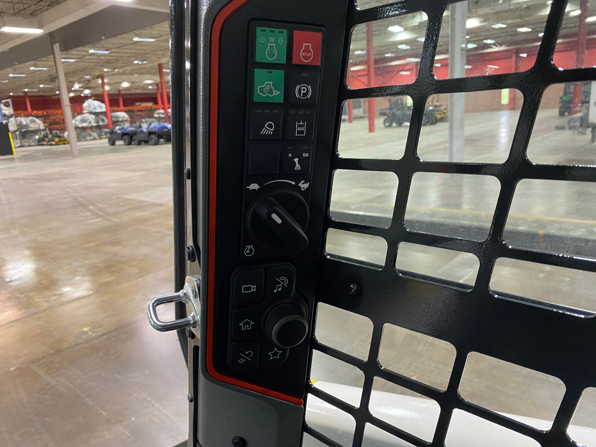 Control panel with switches and dials inside a machine's safety cage, red and black colors visible.