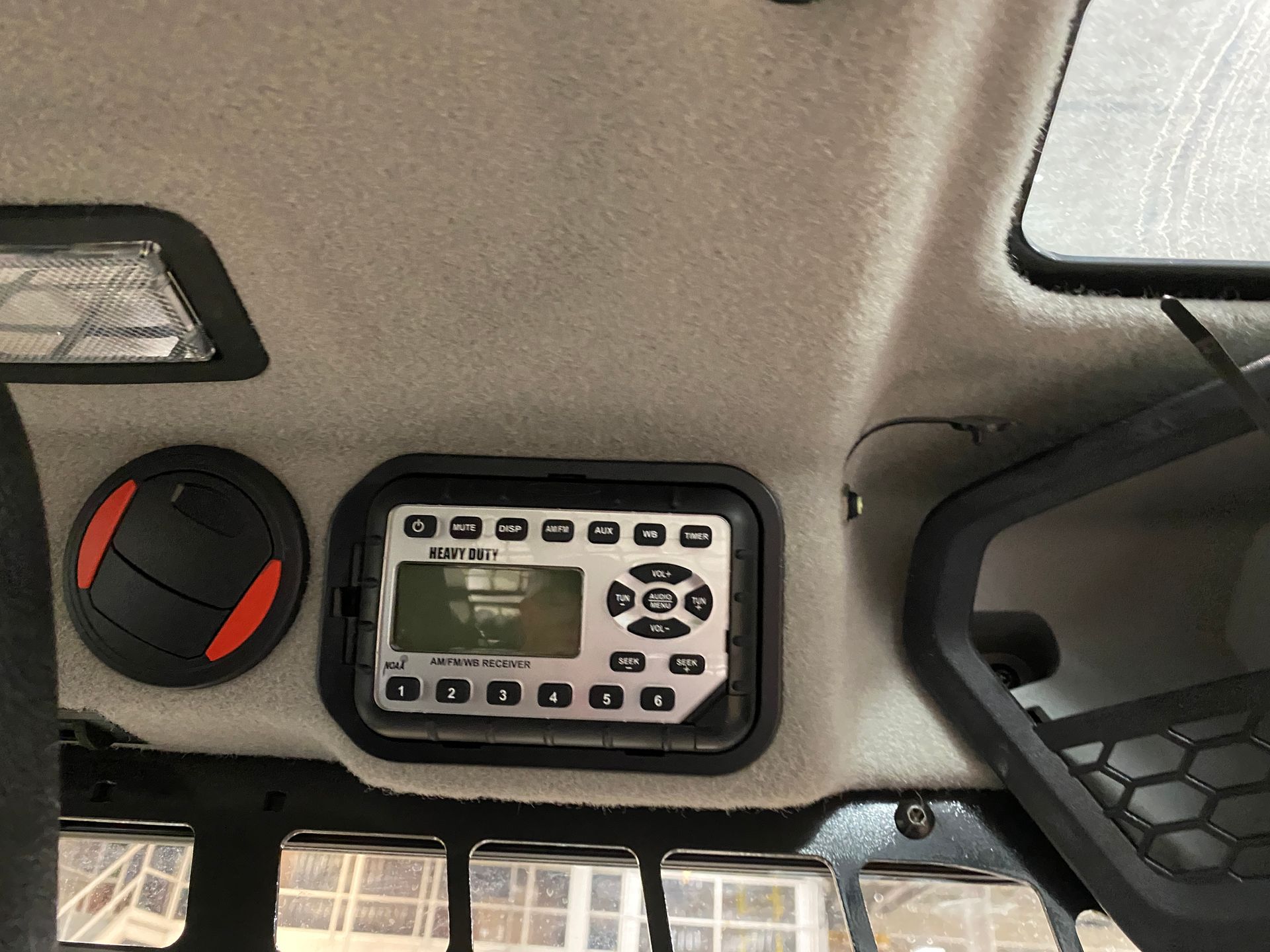 Interior of a vehicle's ceiling: radio, air vent, and mesh pocket visible.