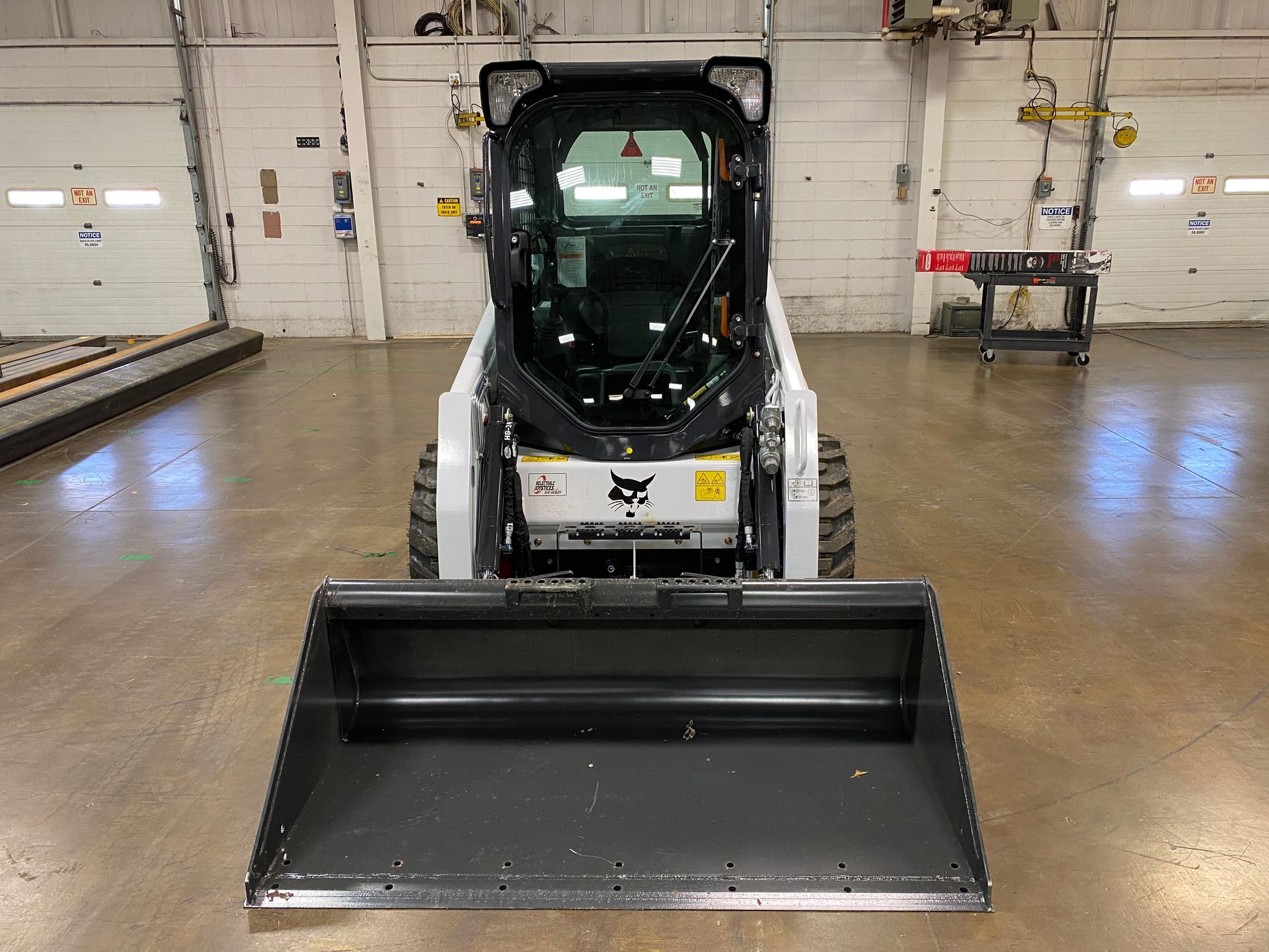 Bobcat skid steer loader with bucket in a warehouse.