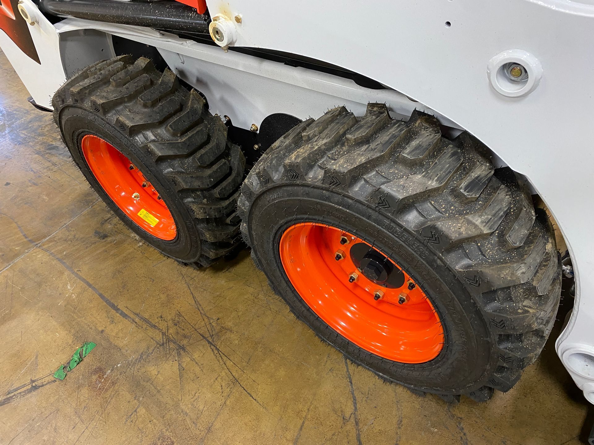 Close-up of a Bobcat skid-steer loader's orange wheels and black treaded tires.