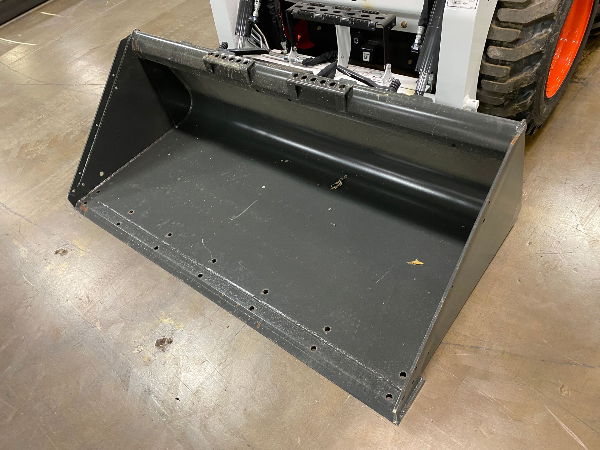 Gray bucket attachment on a skid steer loader.