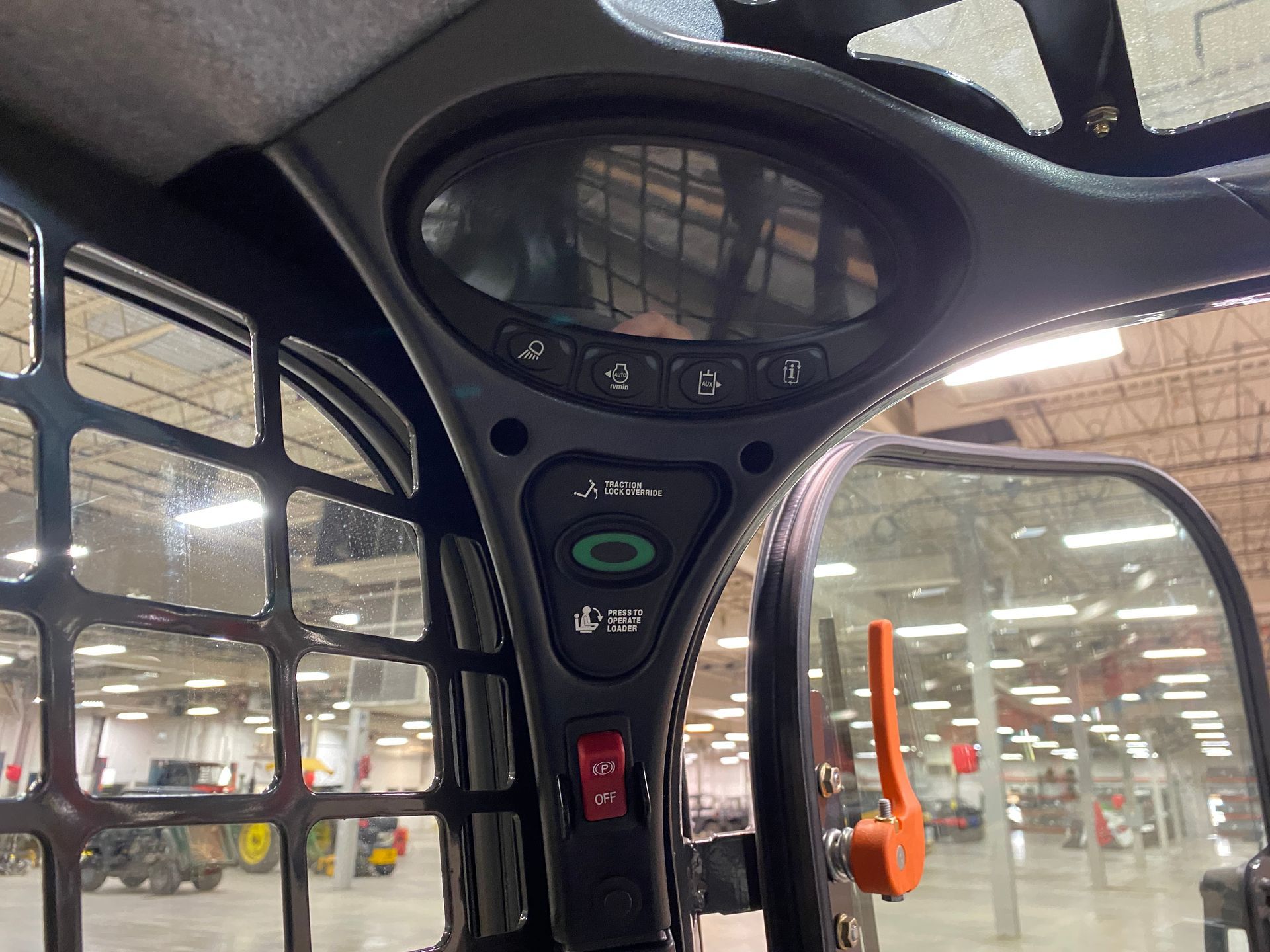 Interior of a skid steer cabin showing a dashboard with gauges and controls.