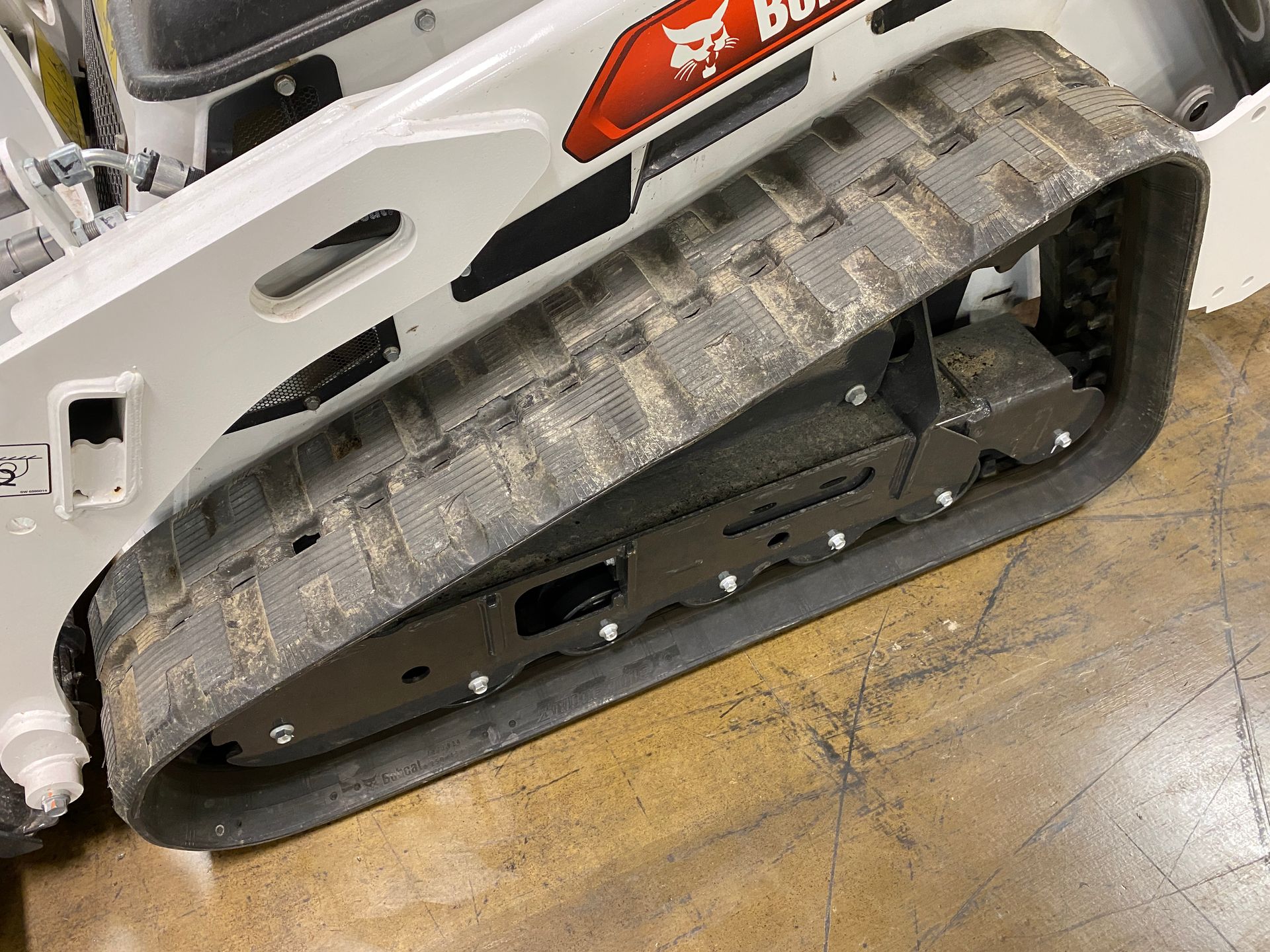Close-up of a Bobcat track on a construction vehicle, covered in dirt and debris.