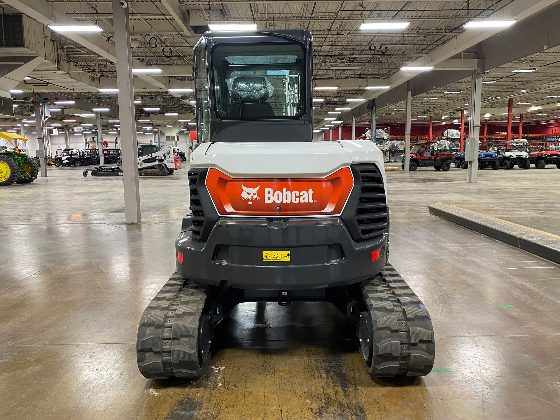 Bobcat compact track loader, viewed head-on in a warehouse.