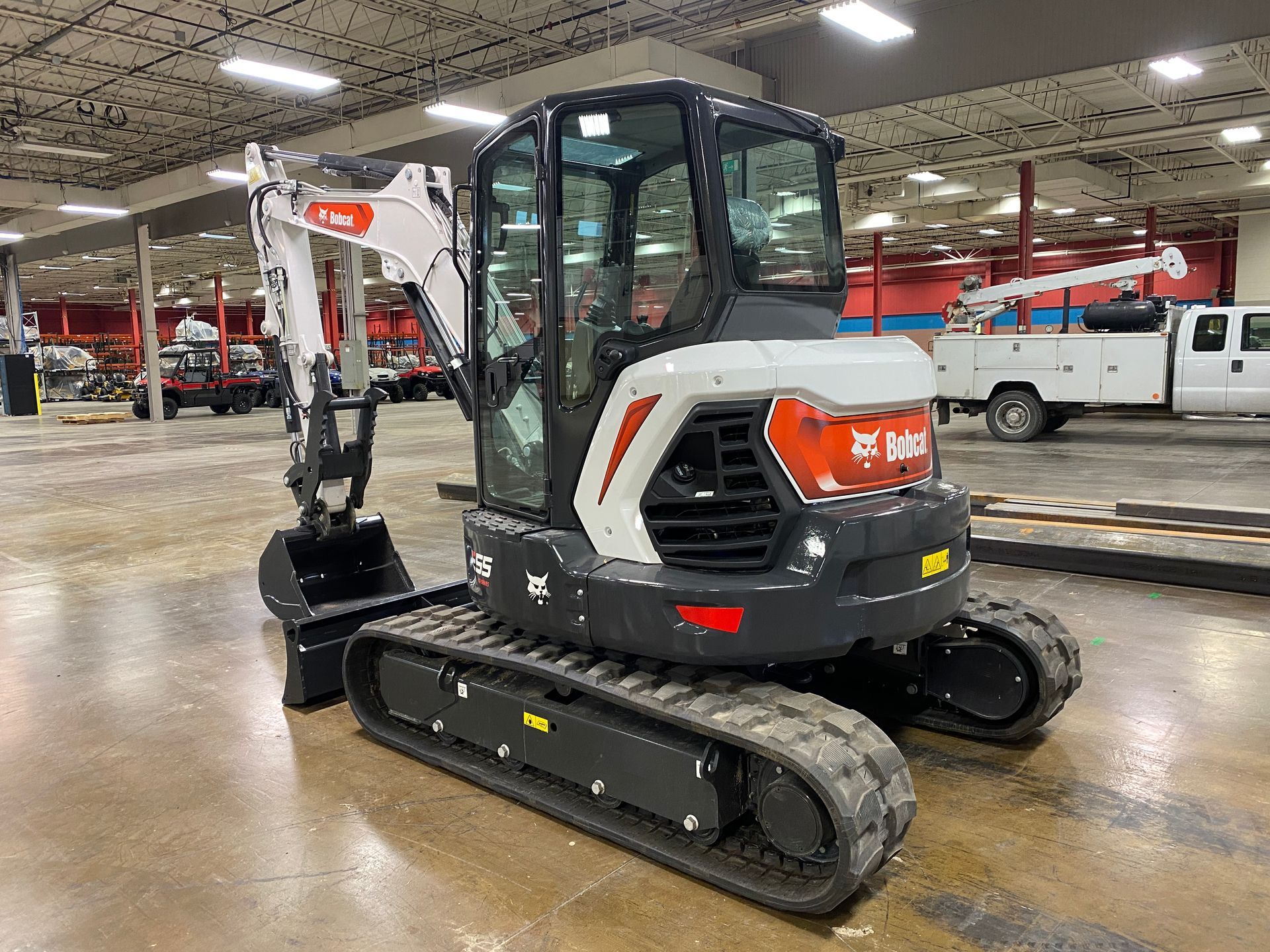 Bobcat mini excavator, white and black, indoors.
