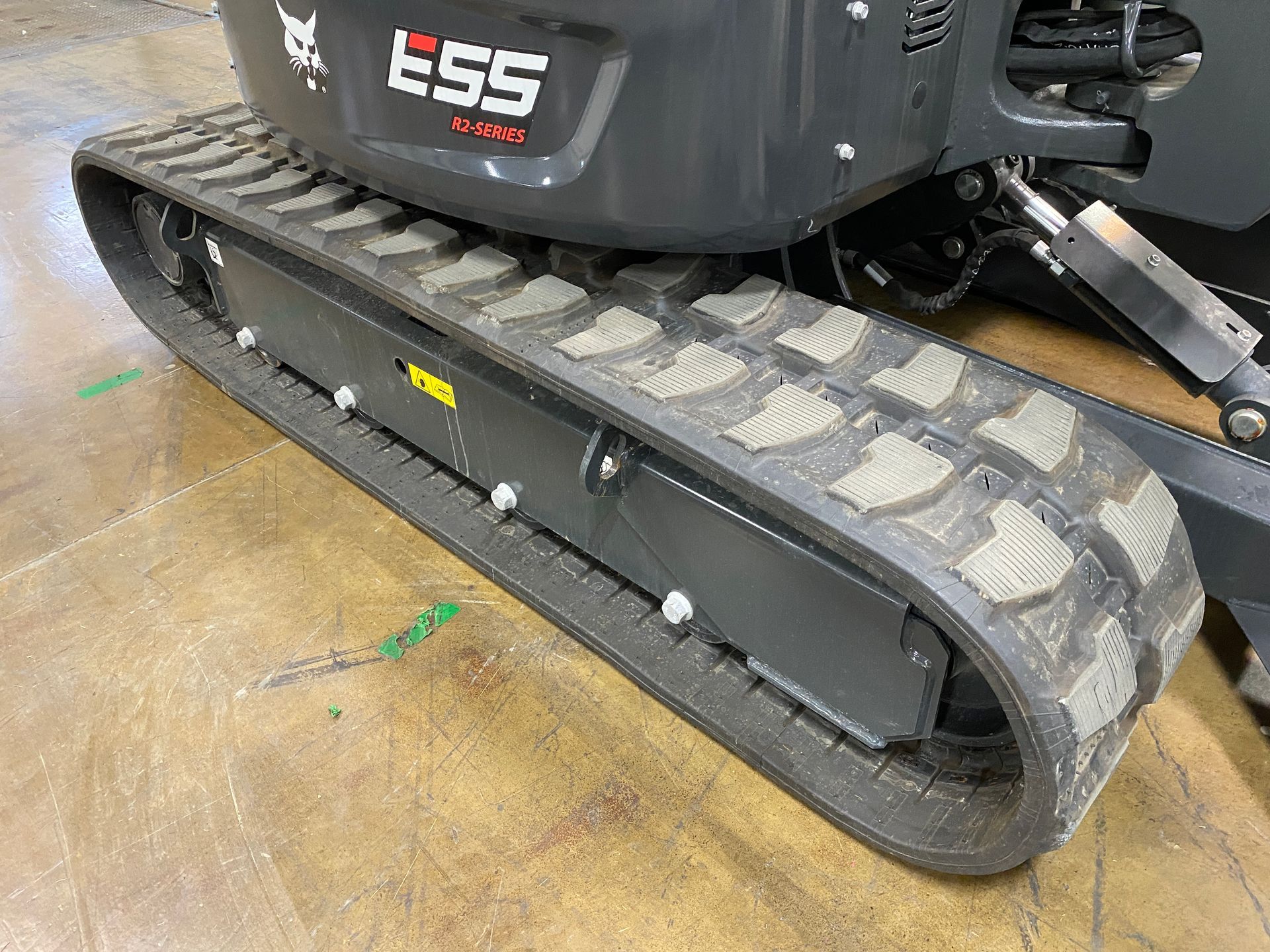 Gray Bobcat E55 mini excavator track on a brown surface.