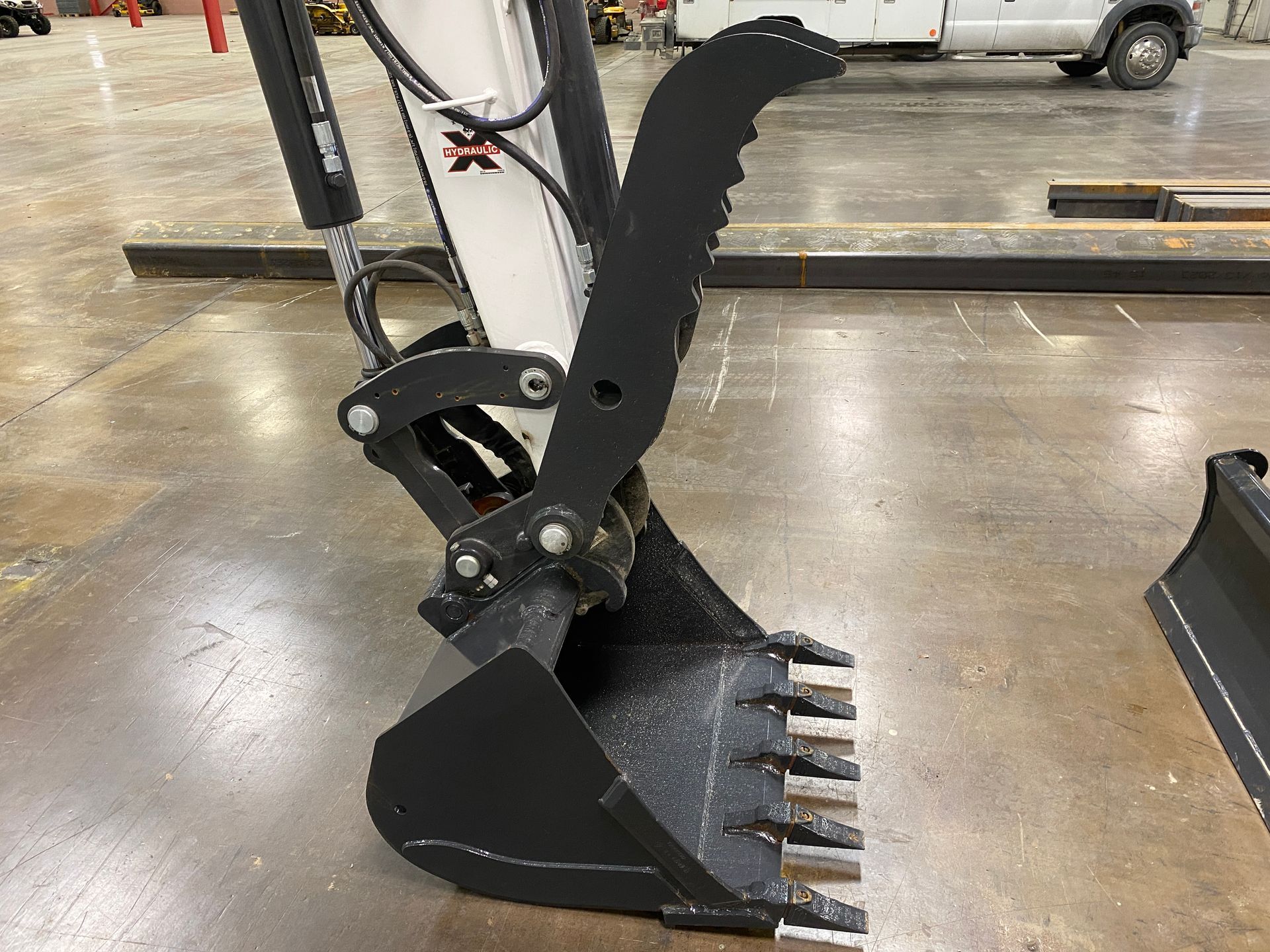 Black excavator bucket with a grapple attachment.