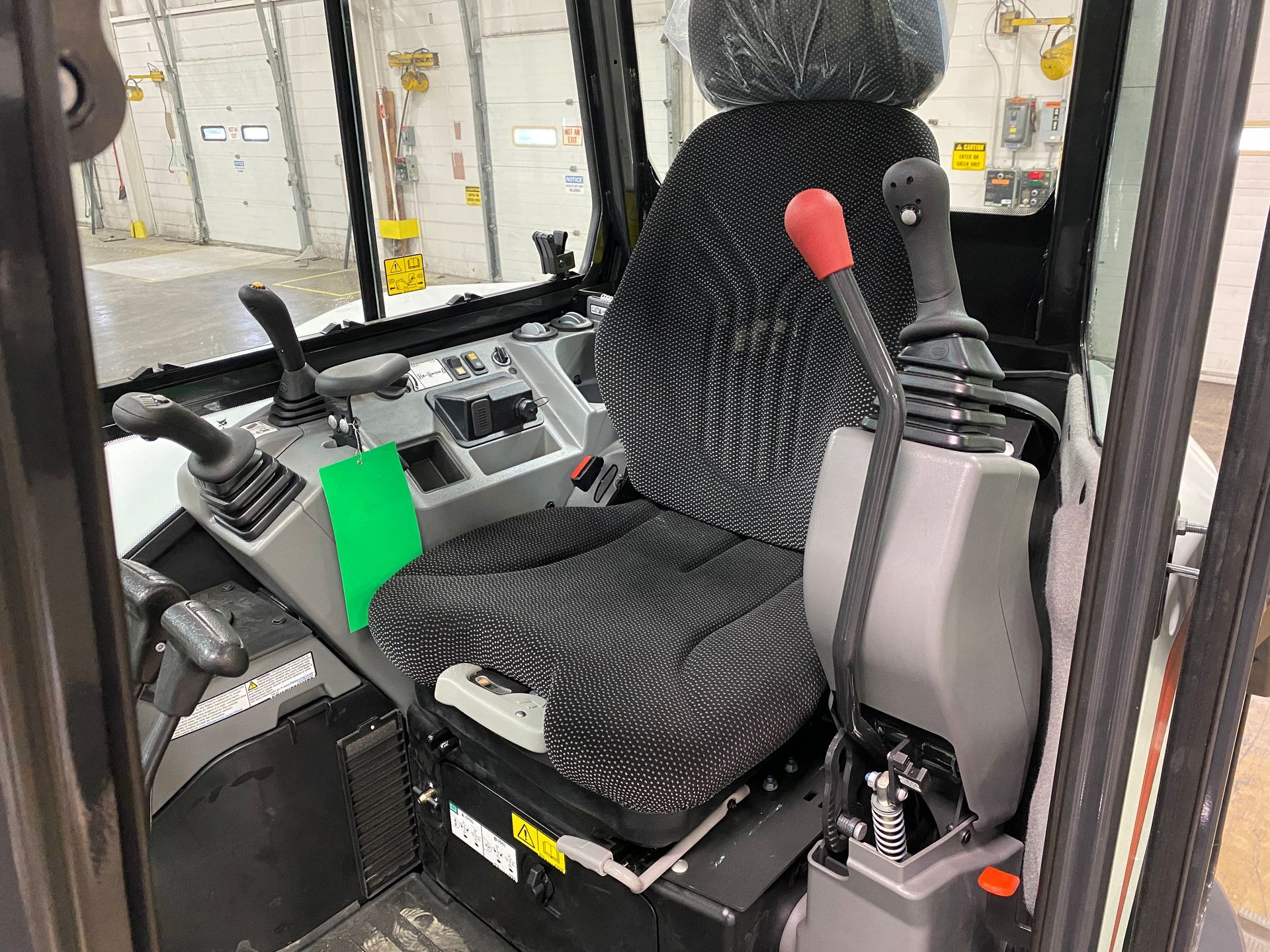 Interior view of a Bobcat excavator cab with seat, controls, and levers.