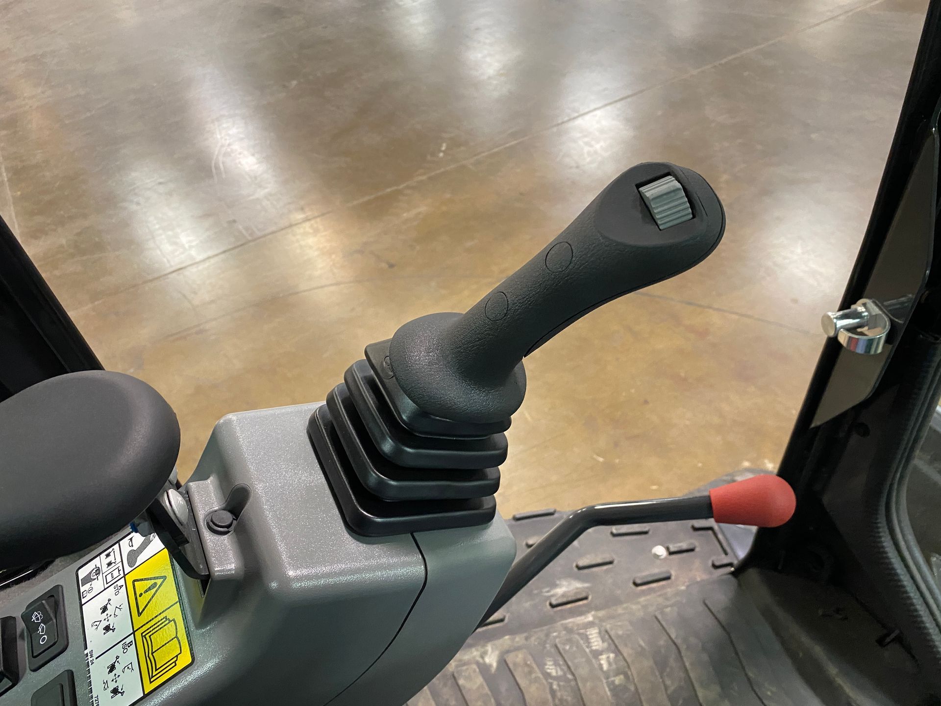 Black excavator joystick and armrest inside cabin.