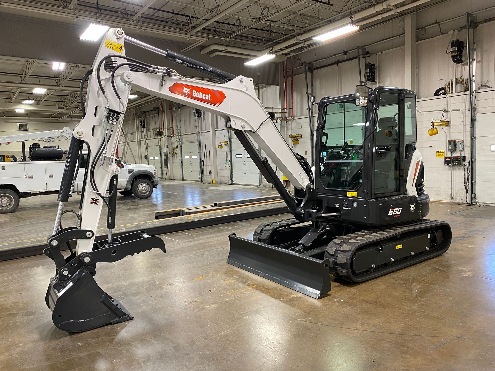 Bobcat mini excavator with black and white paint, inside a warehouse.