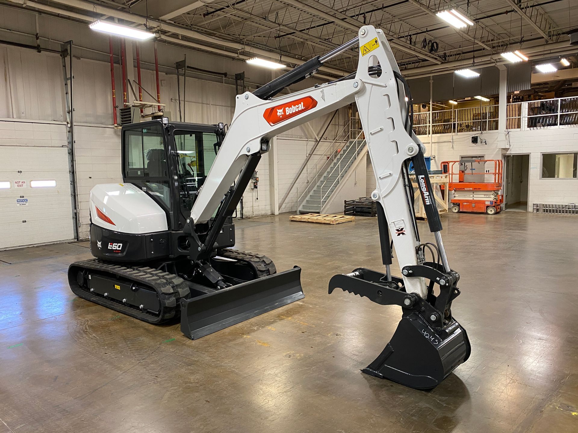 White Bobcat excavator with black tracks and bucket indoors.