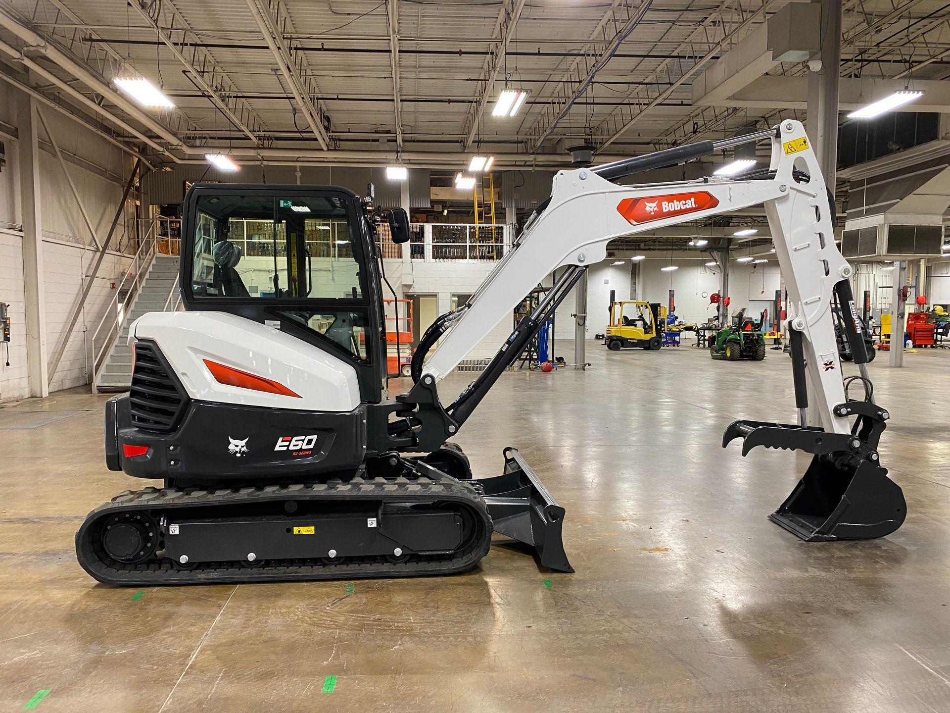 Bobcat E20 excavator, white and black, indoors, bucket lowered.