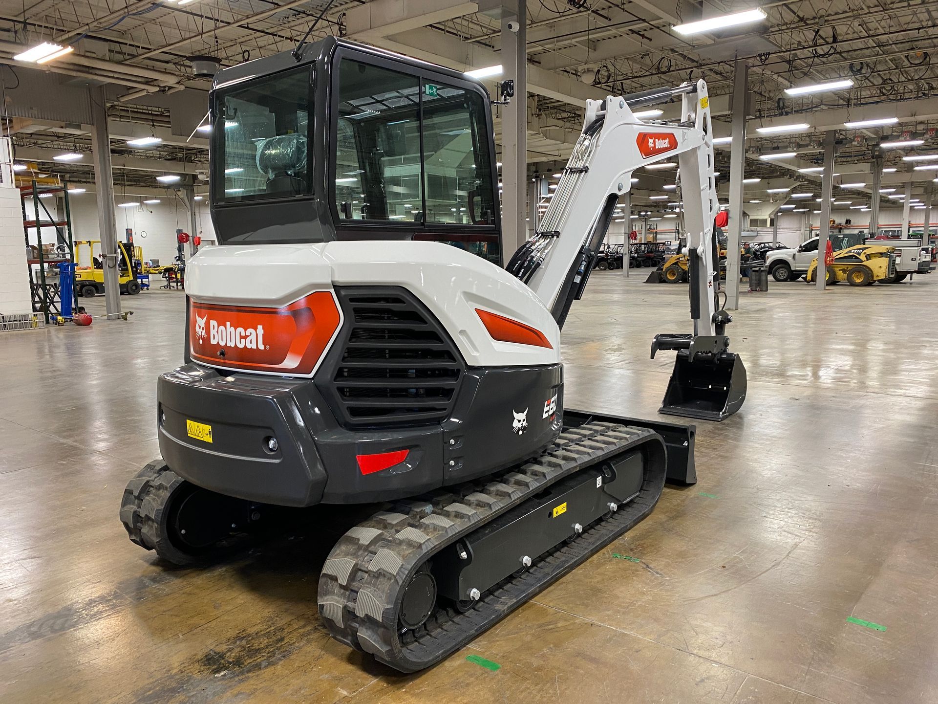 A Bobcat E42 compact excavator in a warehouse setting. White and gray with tracks.