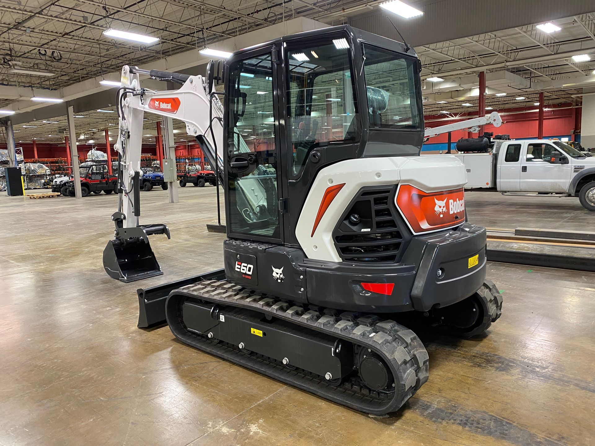 A Bobcat E30 compact excavator with black tracks, white and black body, inside a showroom.