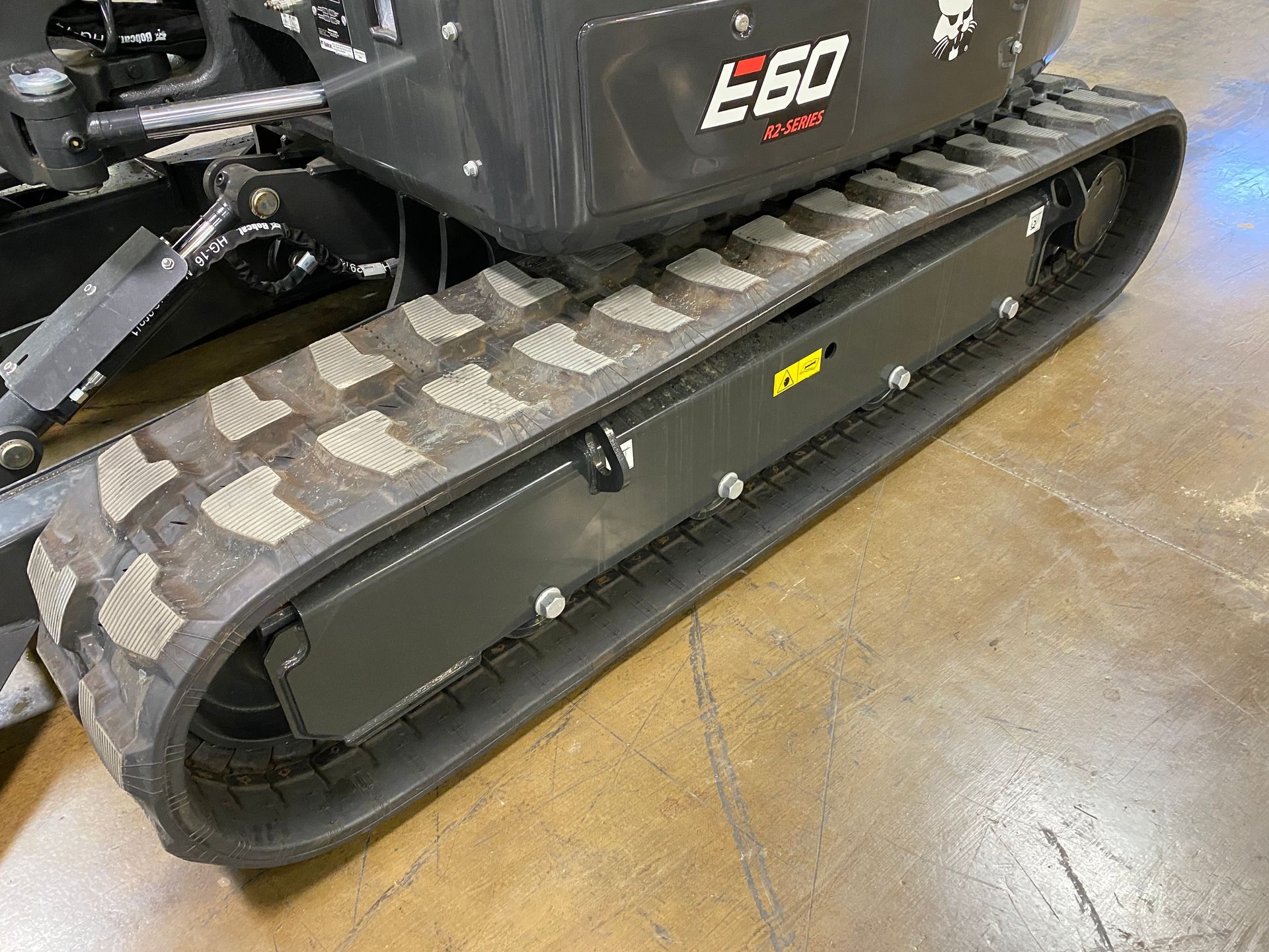 Black compact excavator track on a concrete floor.