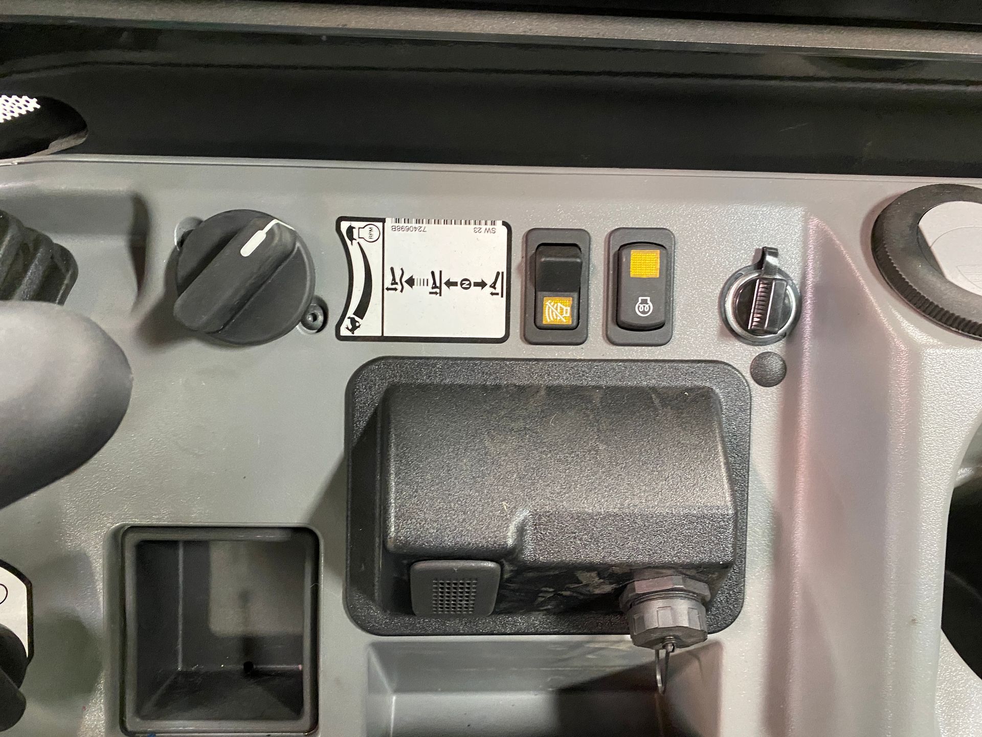 Dashboard panel with knobs, switches, a key, and a 12-volt power outlet on a gray surface.