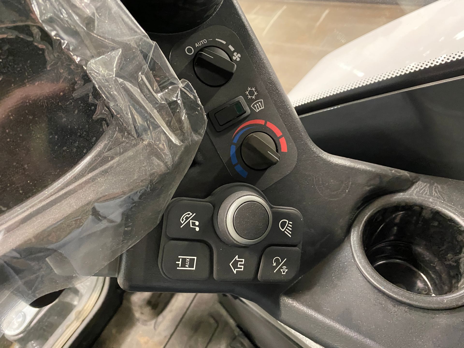 Control panel with knobs and buttons, including lights and temperature, in a vehicle.