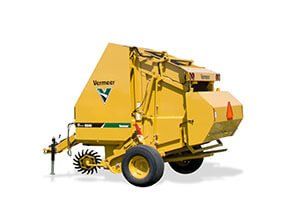 Yellow Vermeer hay baler in a field, ready to collect hay.