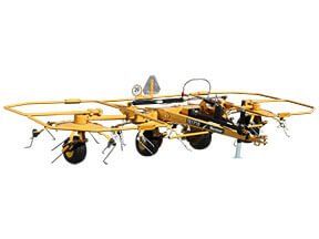 Yellow agricultural hay rake machine, outdoors.