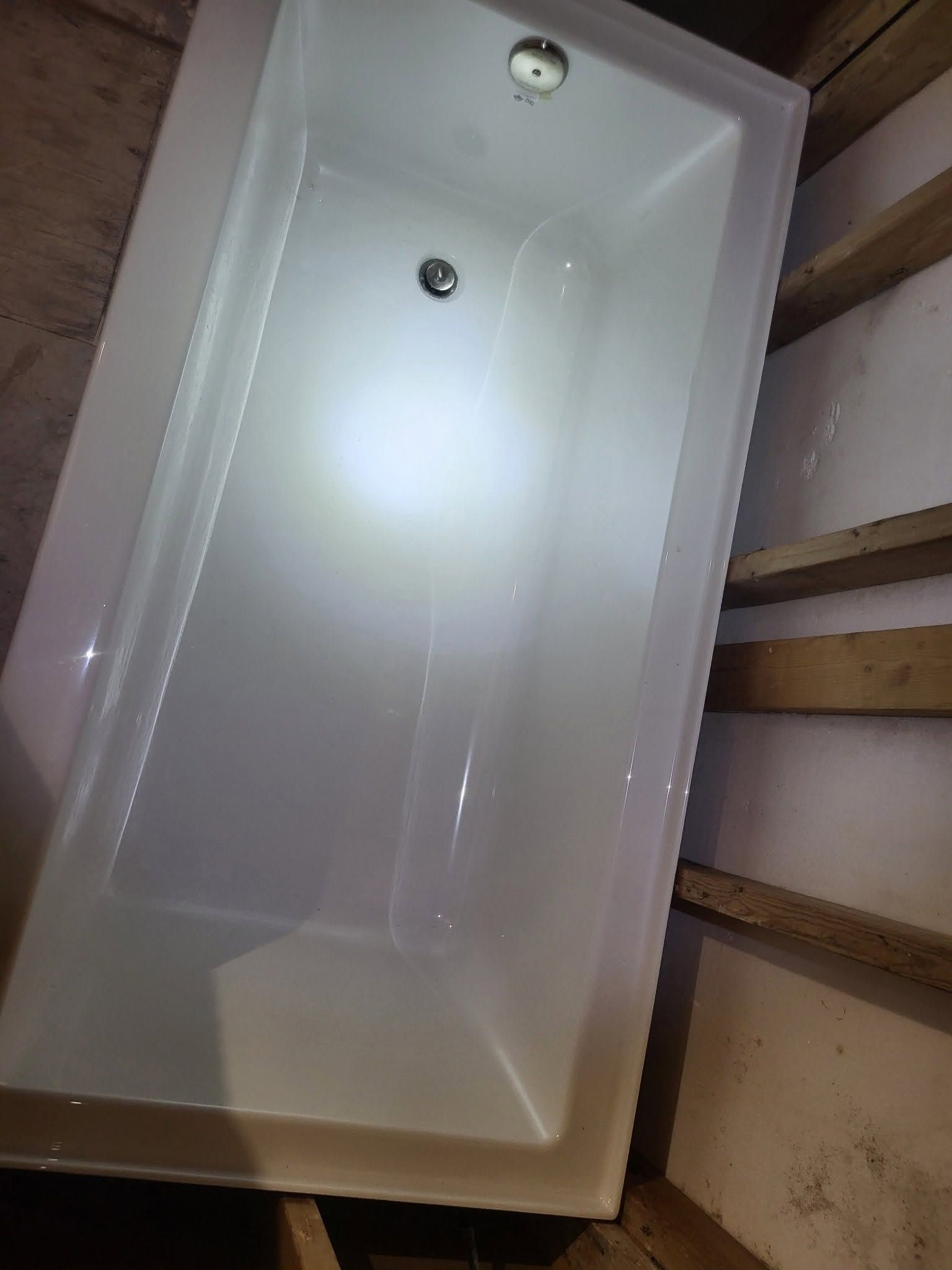 White rectangular bathtub in a bathroom, viewed from above.