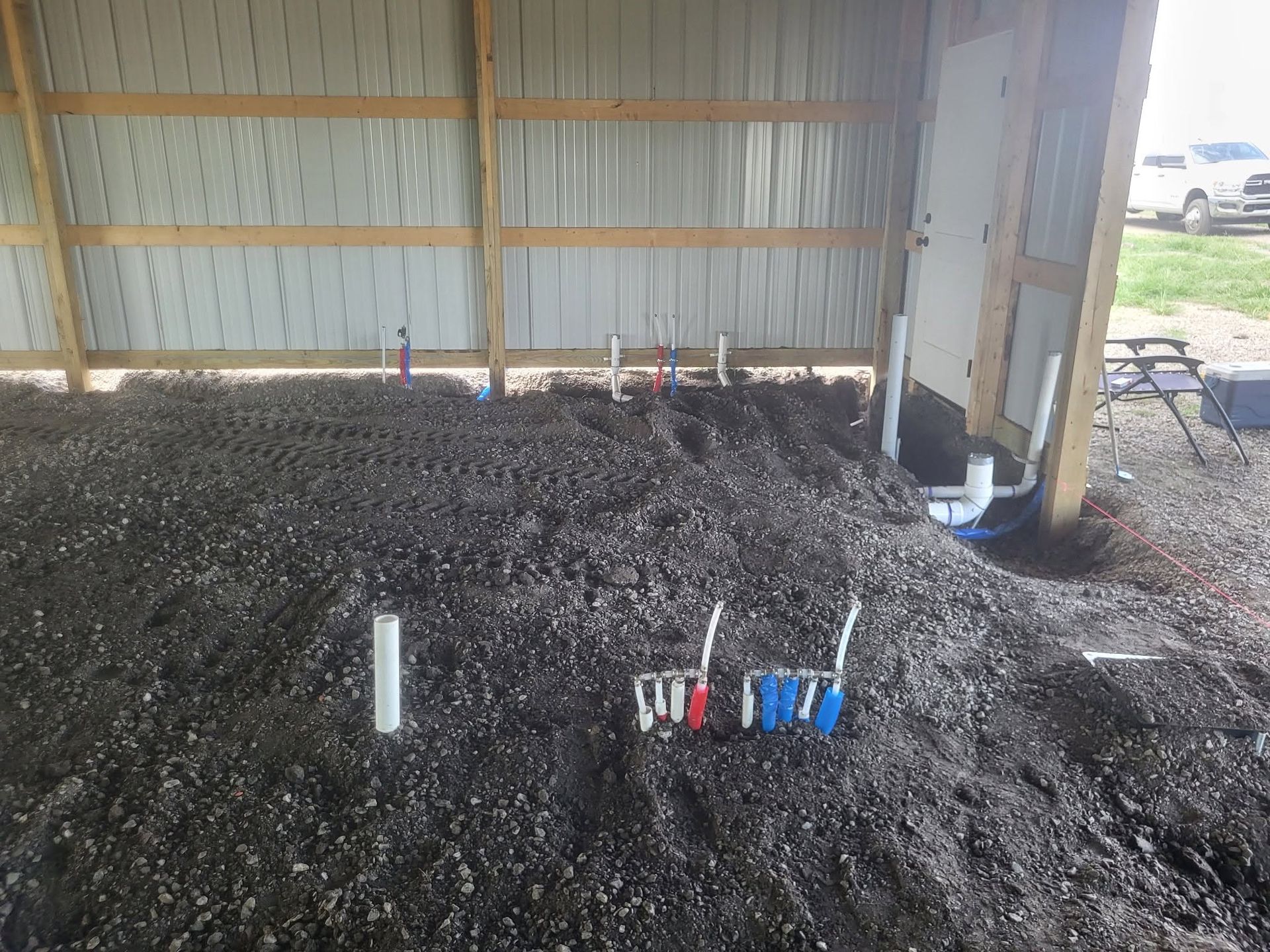 Dirt mound with white pipes and multicolored markers inside a shed-like structure